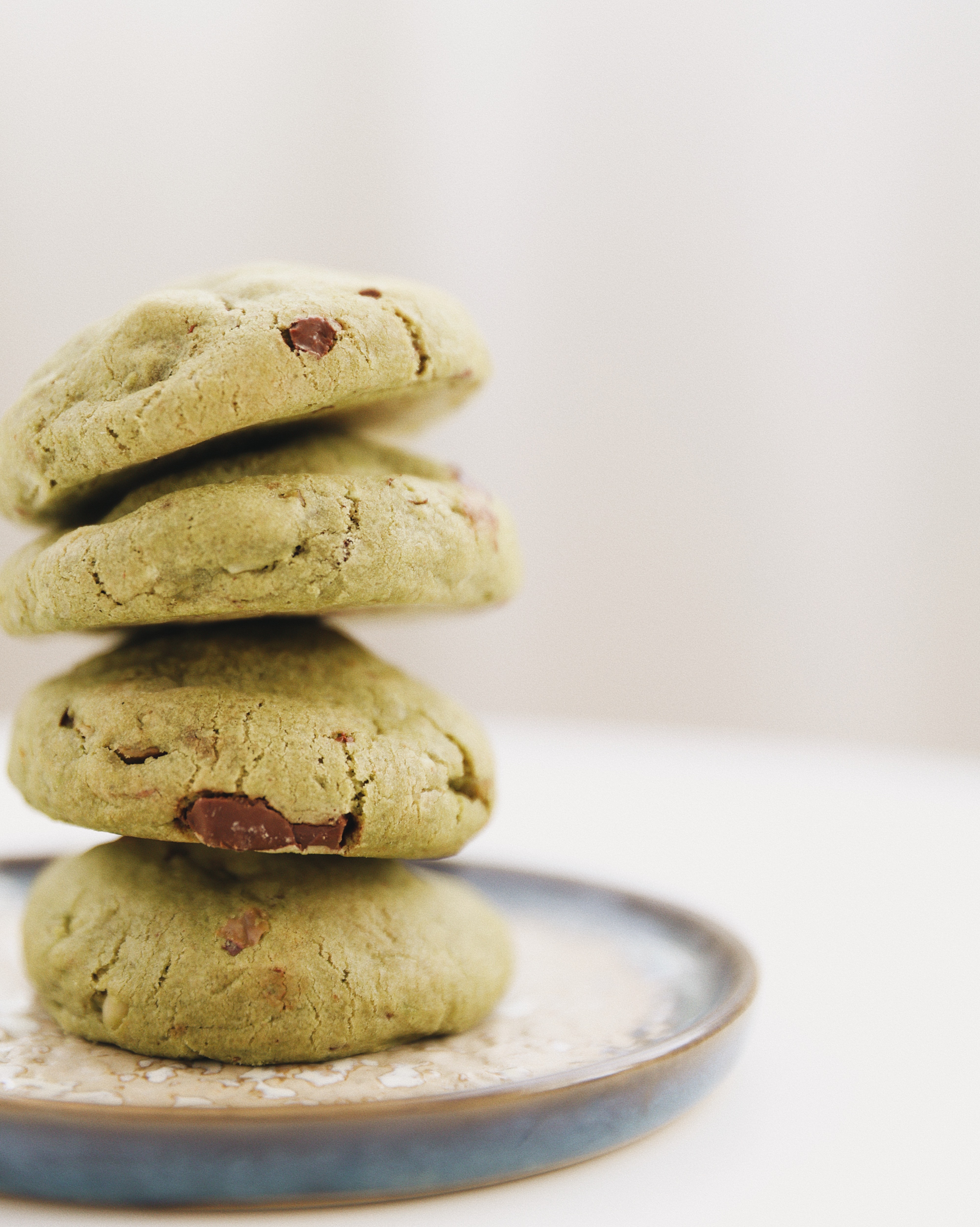 Stack of soft matcha chocolate chip cookies on a ceramic plate.
