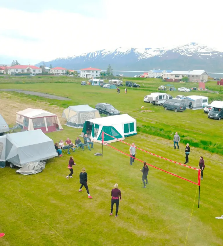 Aerial view of guests playing volleyball at the beachfront campsite in Hauganes.