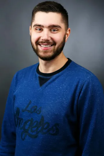 Portrait of man in blue Los Angeles sweatshirt on dark background.