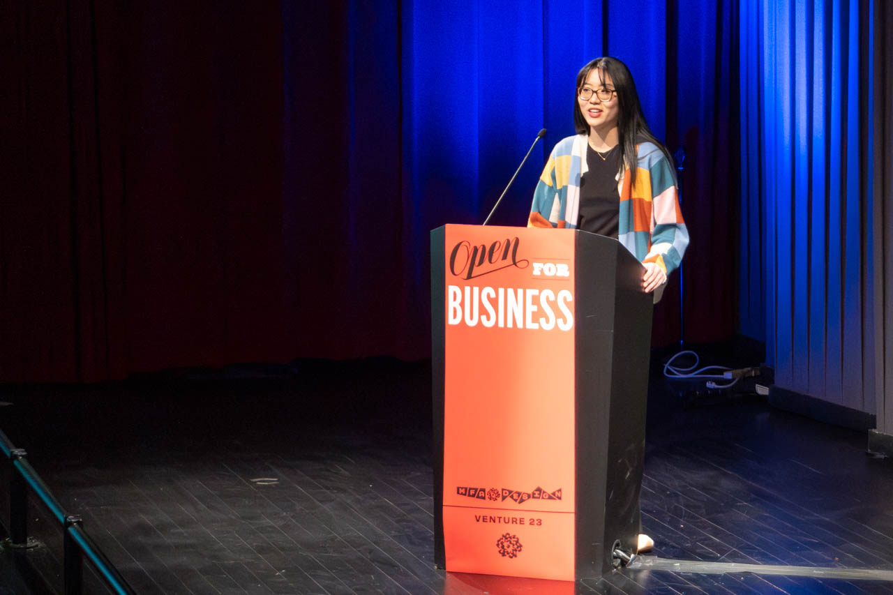 woman standing at a podium delivering a presentation