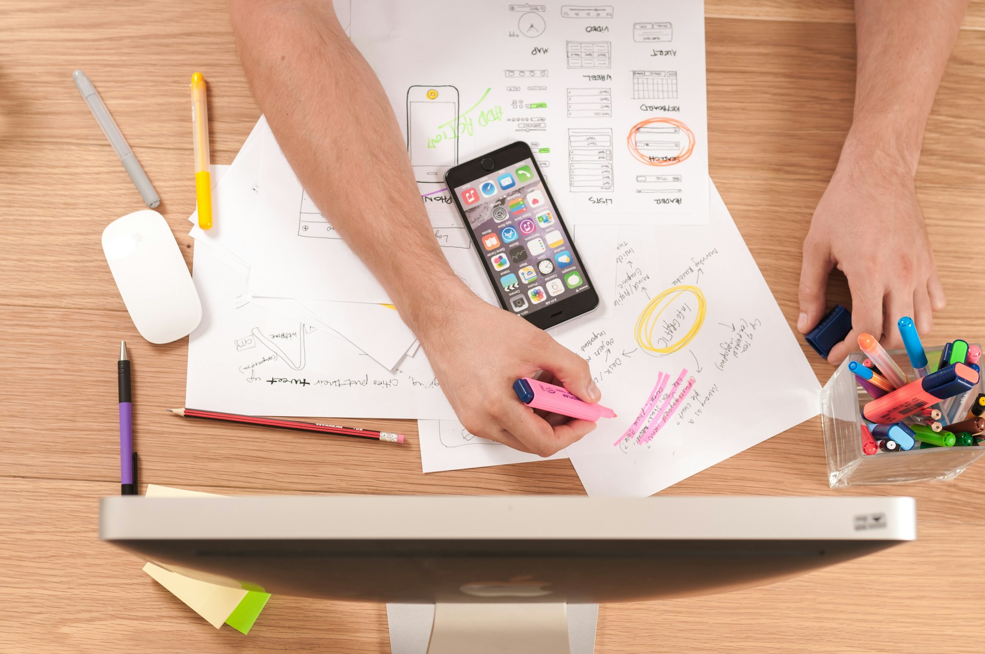 Person working at a desk with a computer, phone, and papers.