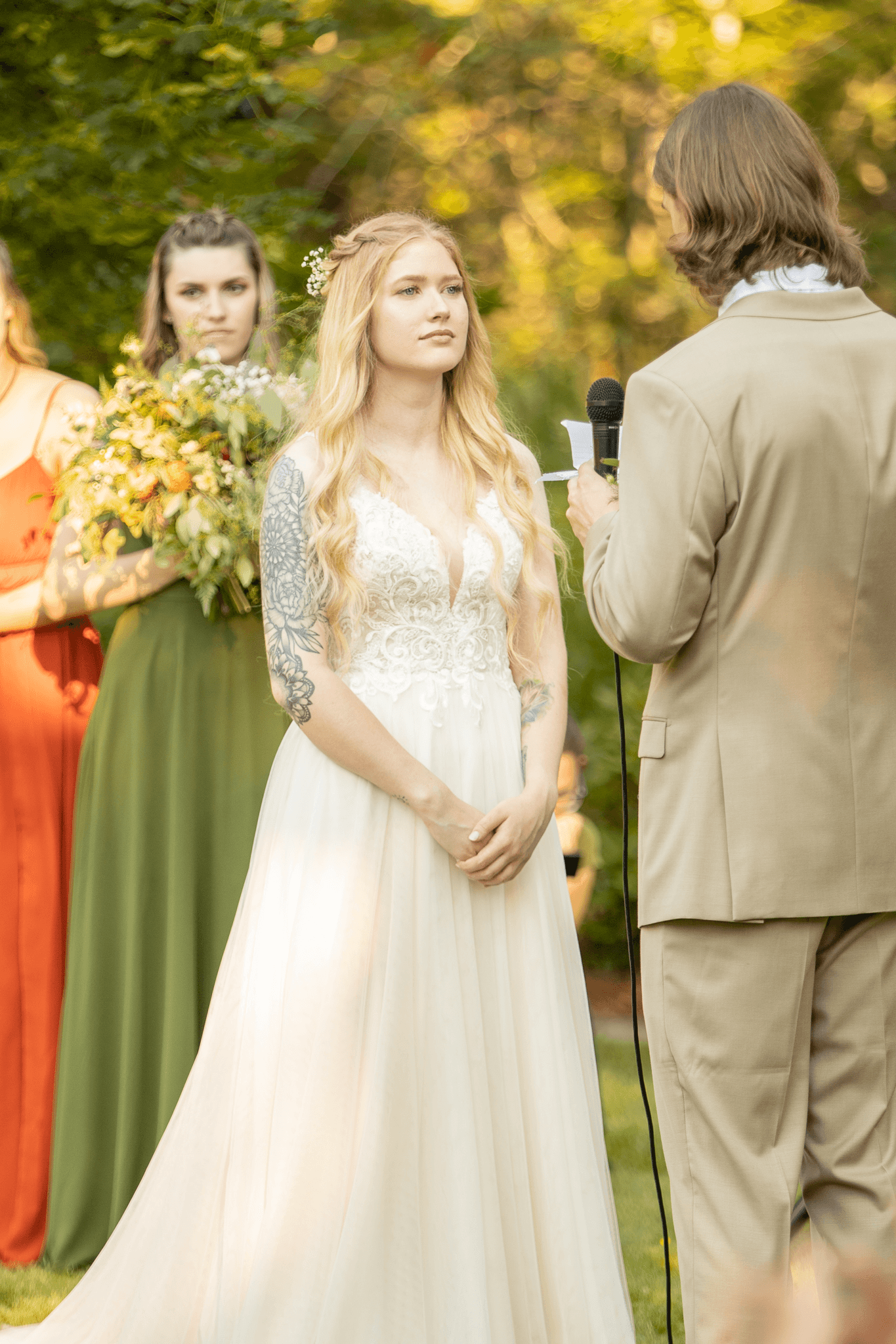  a woman in a white dress, standing next to her groom with her bridesmaids behind her