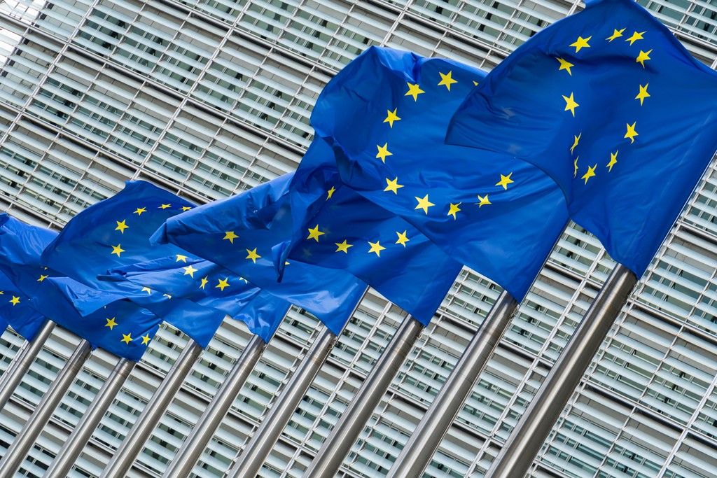 three european flags flying in front of a building