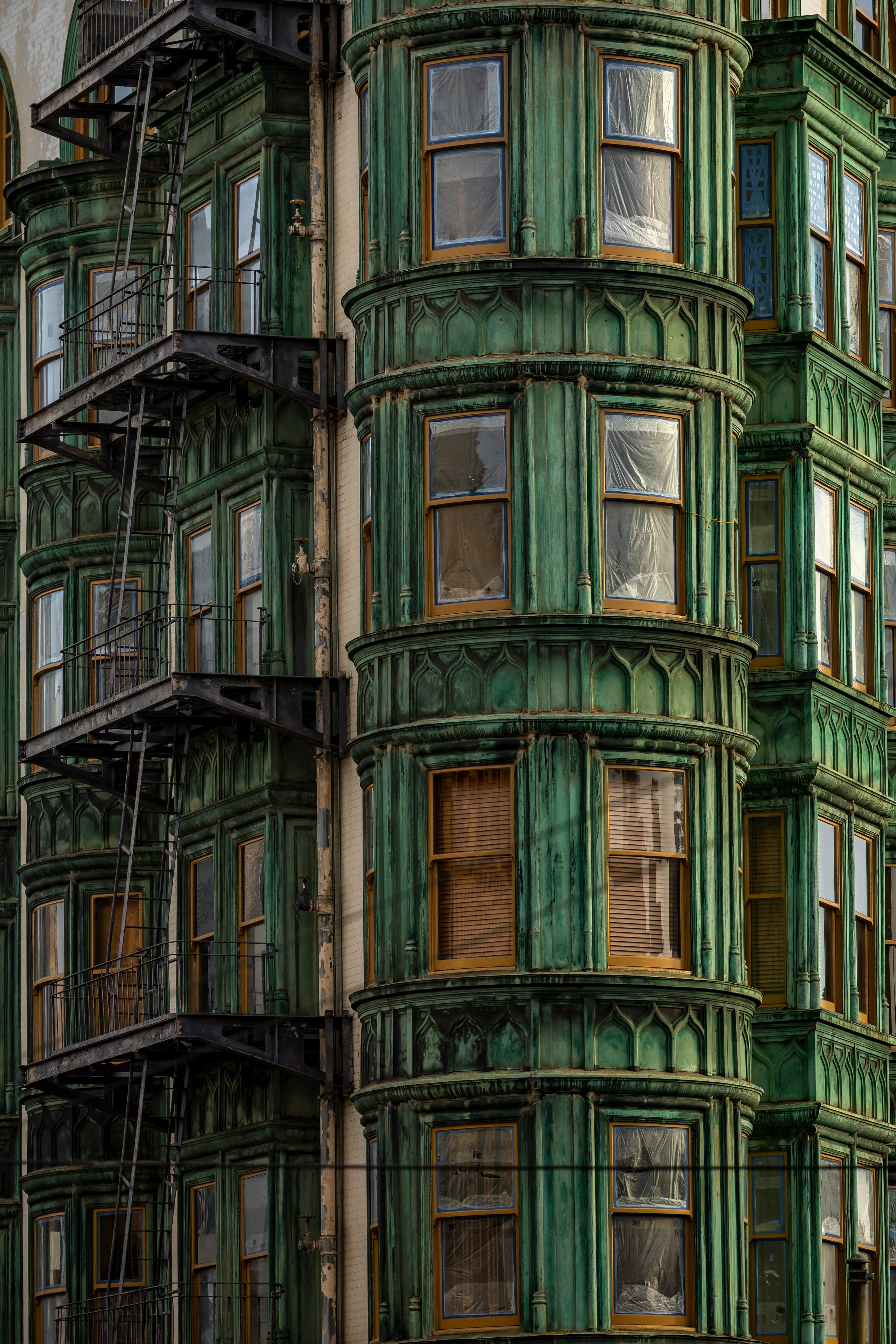 Ornate green building with bay windows and fire escape