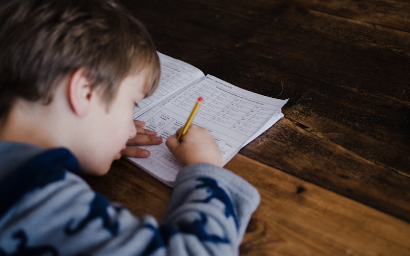 A young child concentrating while practicing a fine motor task at a table.