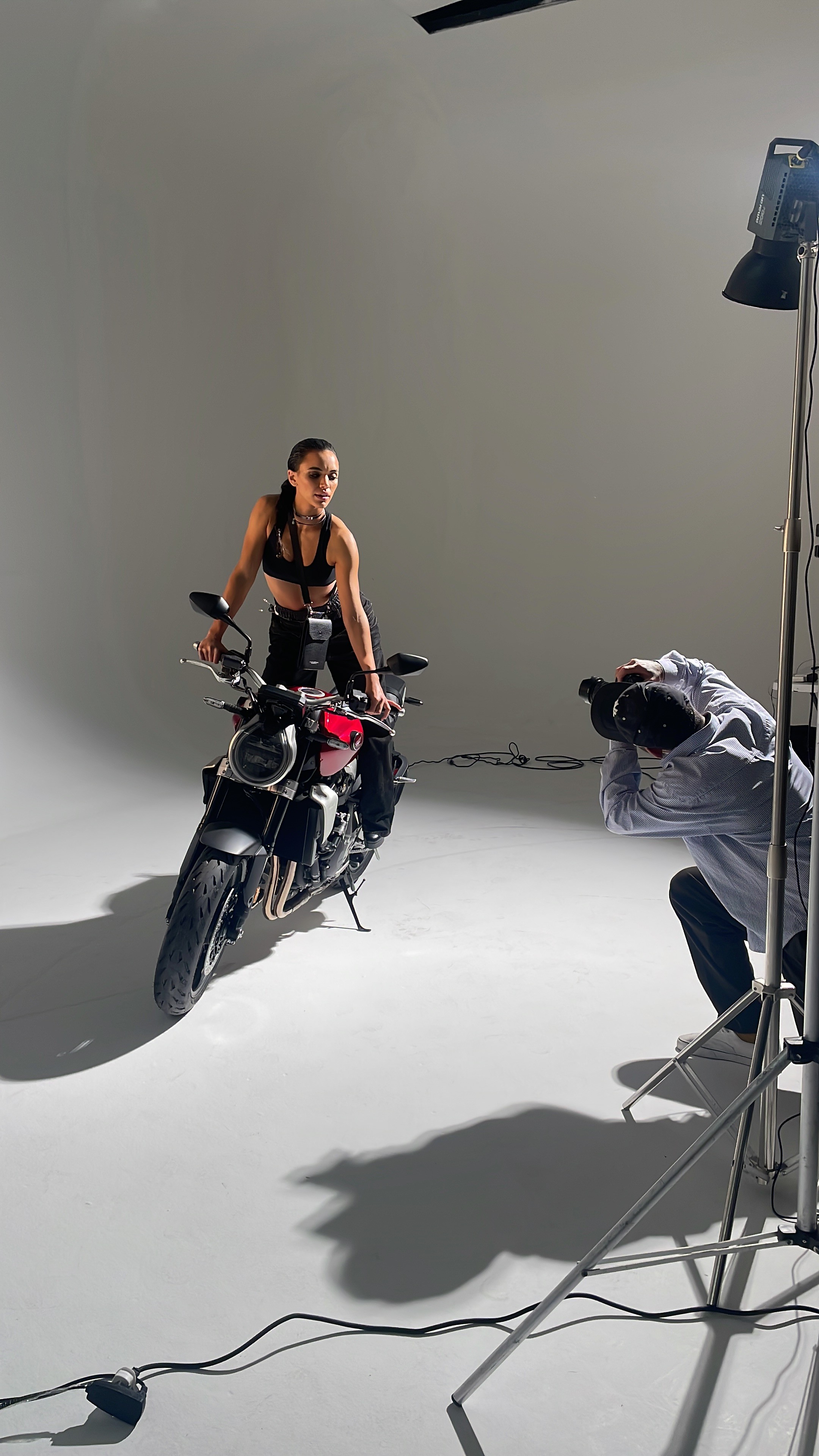 A smiling young man with crossed arms, wearing a plaid shirt and white t-shirt, poses against a dark background.