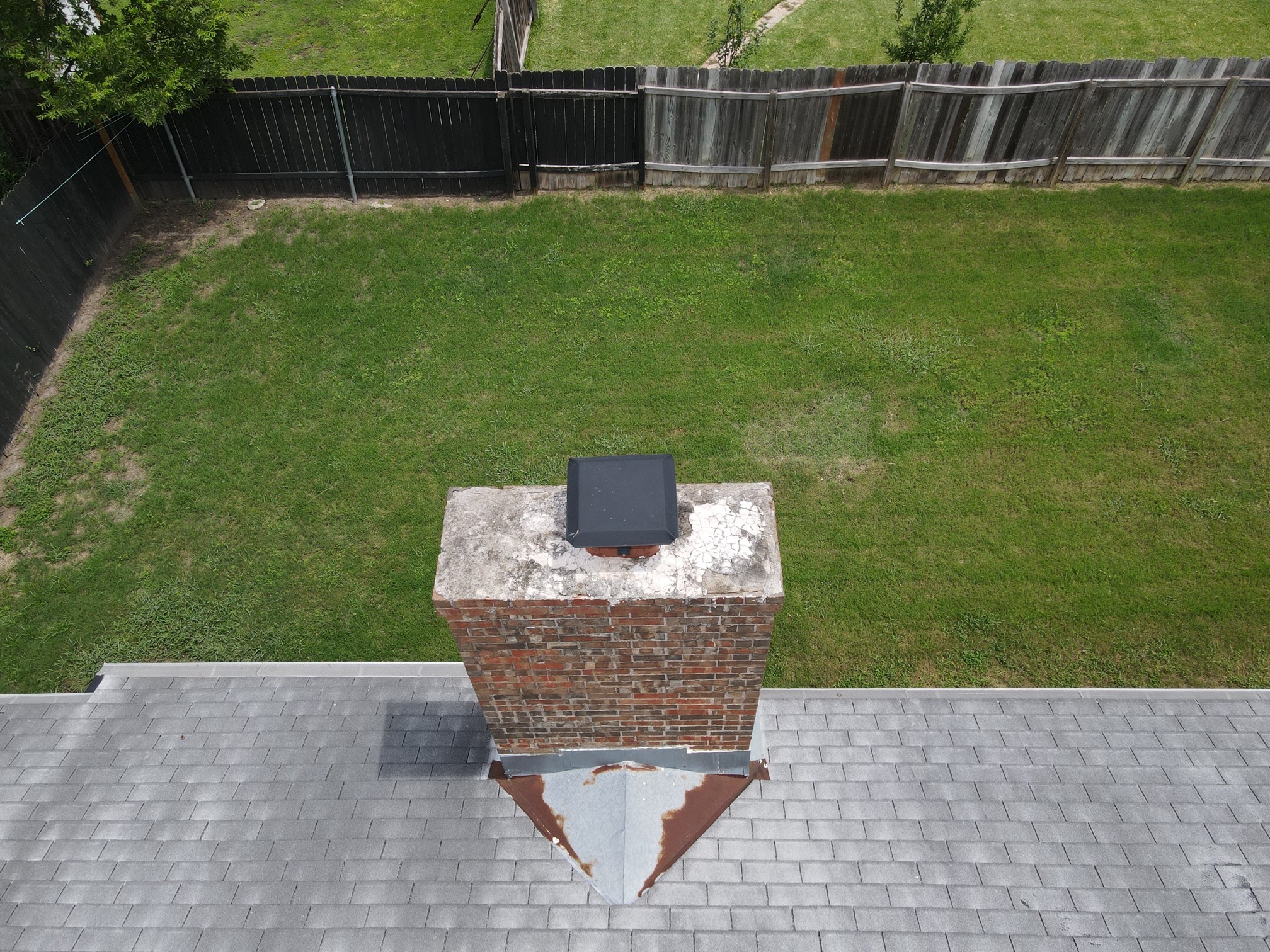Before repair: weathered metal cricket and chimney flashing on the same roof later shown with green shingles.