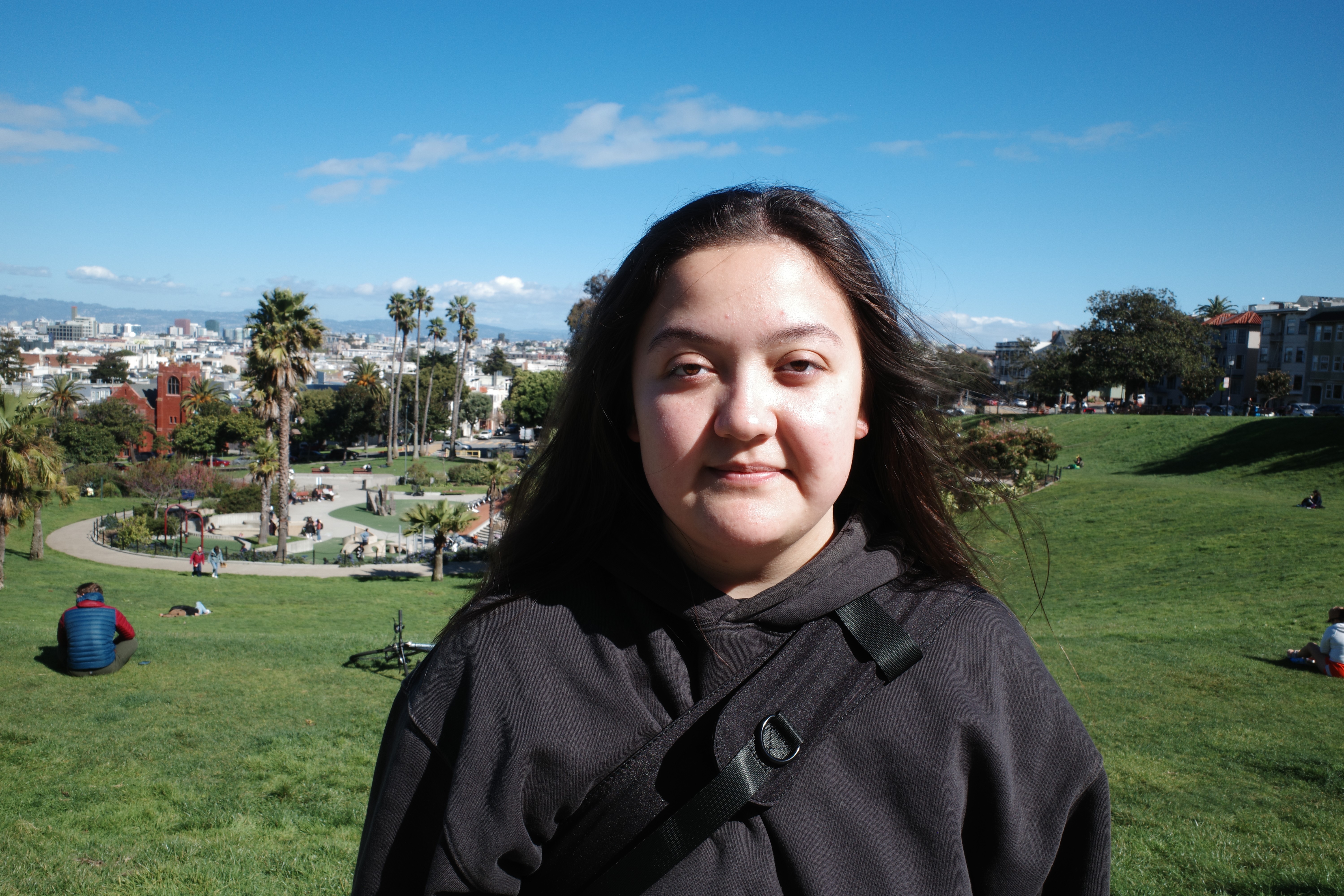 A thoughtful young person with dark hair gazes to the side, captured in soft black and white lighting.