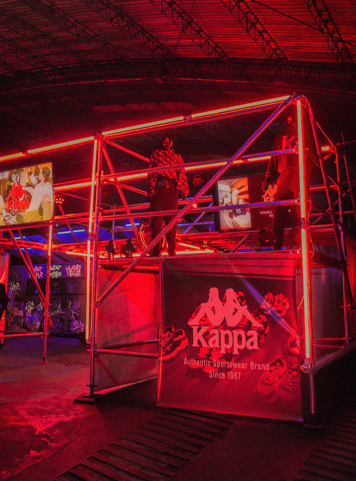 A vibrant esports arena with red lighting and a gaming setup featuring two players at a stage.