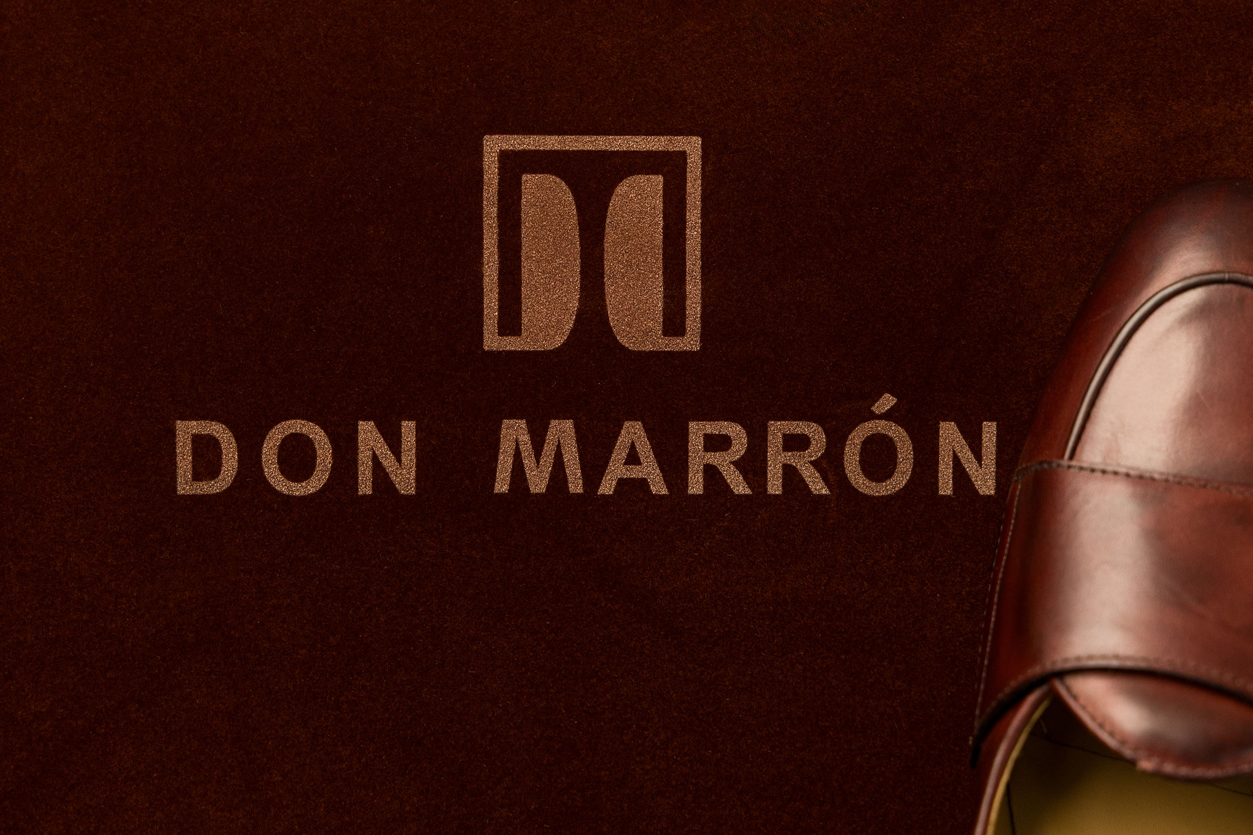 A close-up of Don Marrón’s embossed logo on deep suede — a reflection of timeless craftsmanship and refined luxury in every detail.