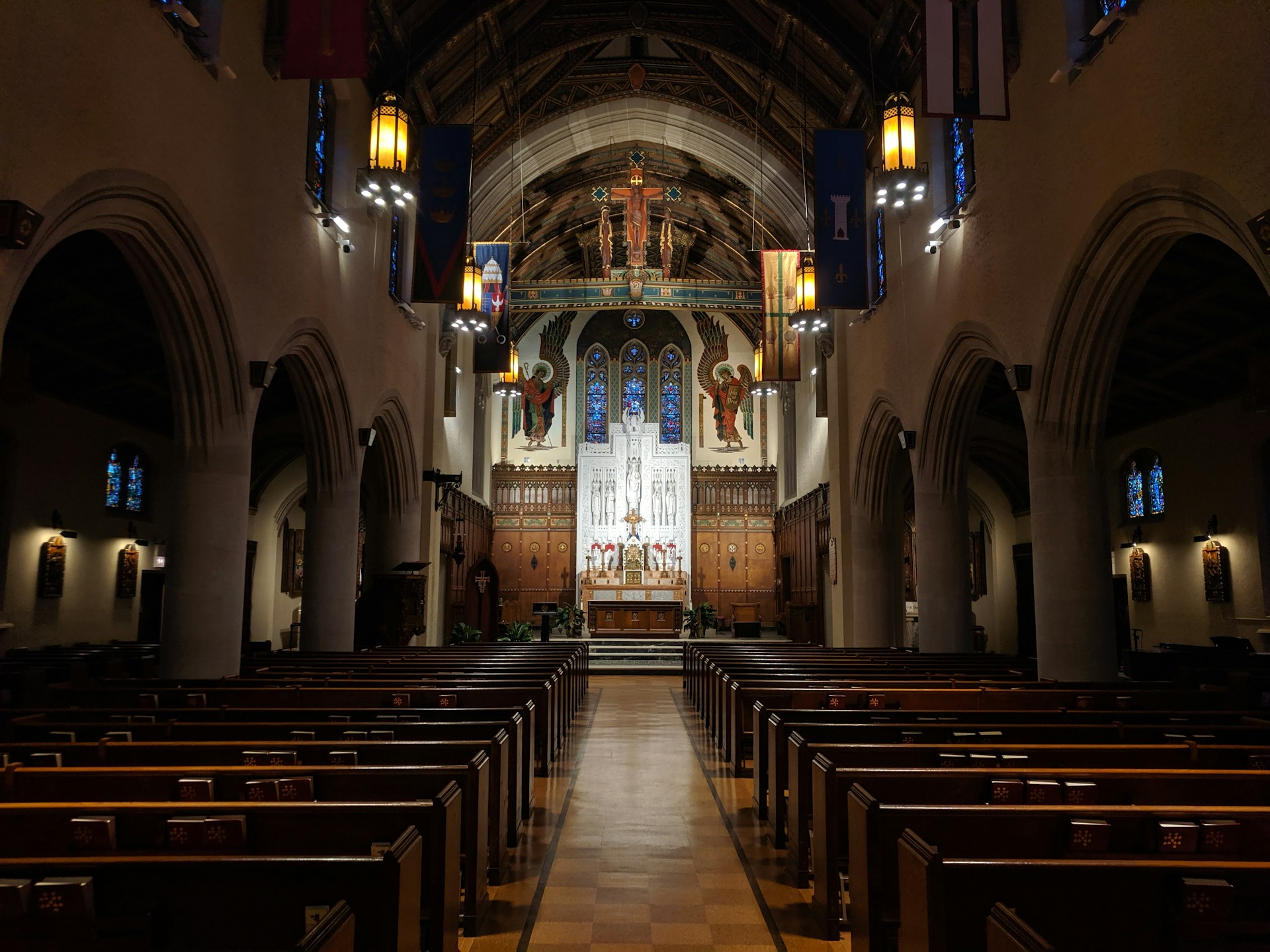 Church interior with traditional pews, stained-glass windows and an illuminated altar, creating a welcoming space for worship and community gatherings.