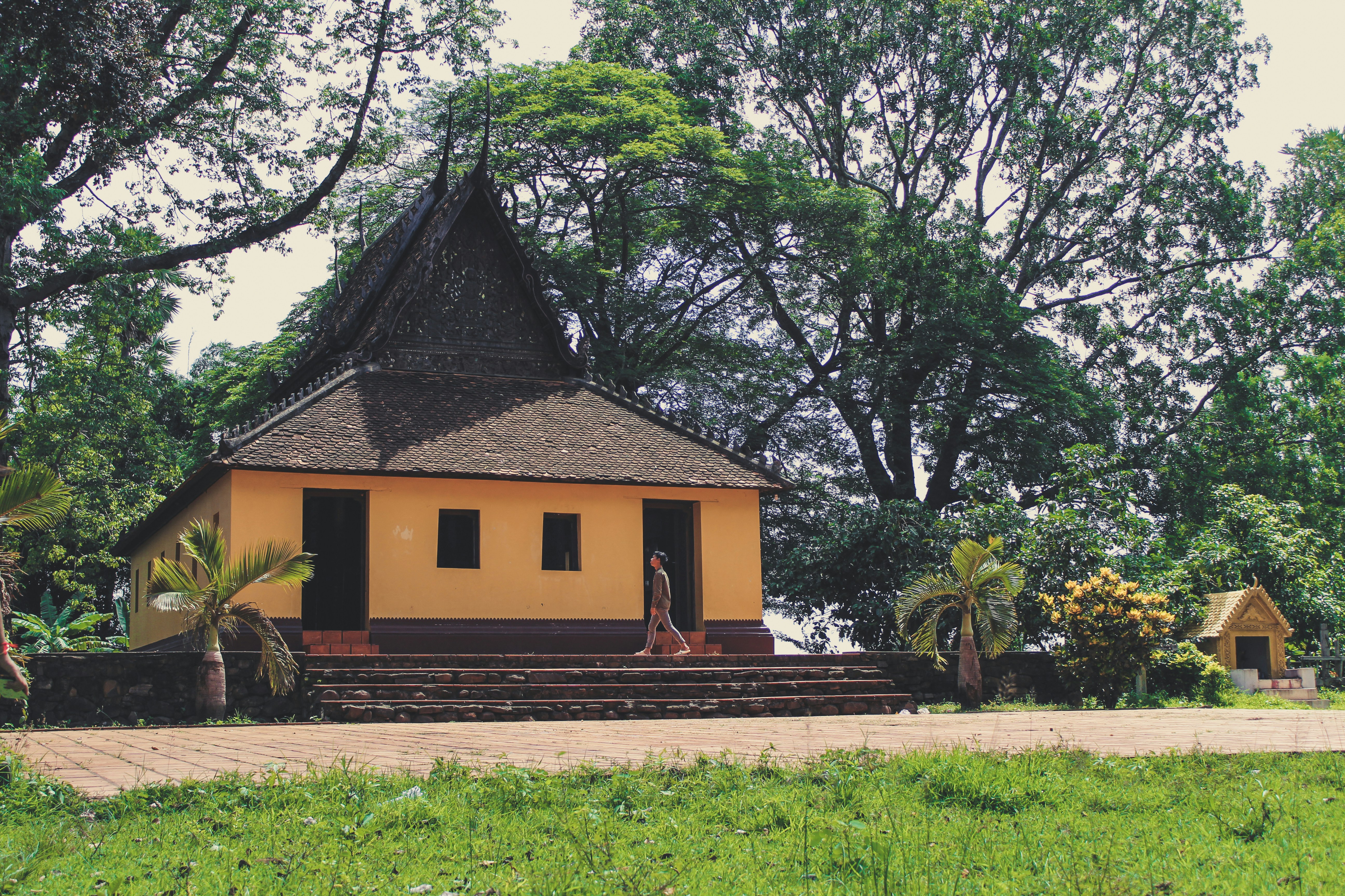 A small yellow building sitting in the middle of a lush green field