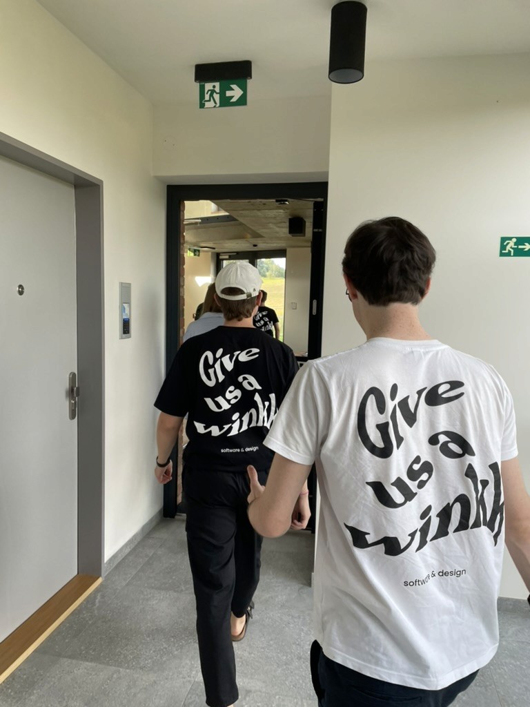 Personen gehen hintereinander im winkk Shirt