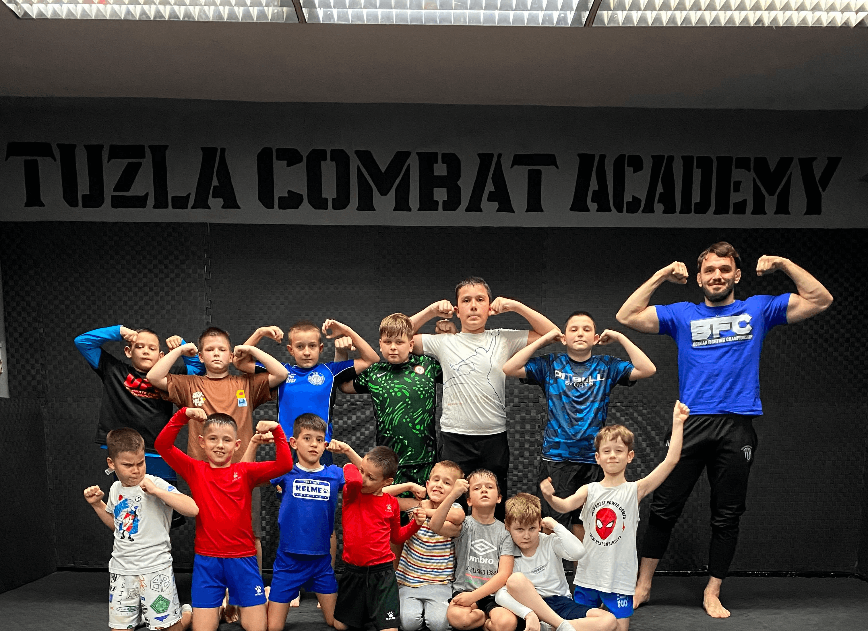 Djeca i trener pozdravljaju se za zajedničku fotografiju ispred loga Tuzla Combat Academy.