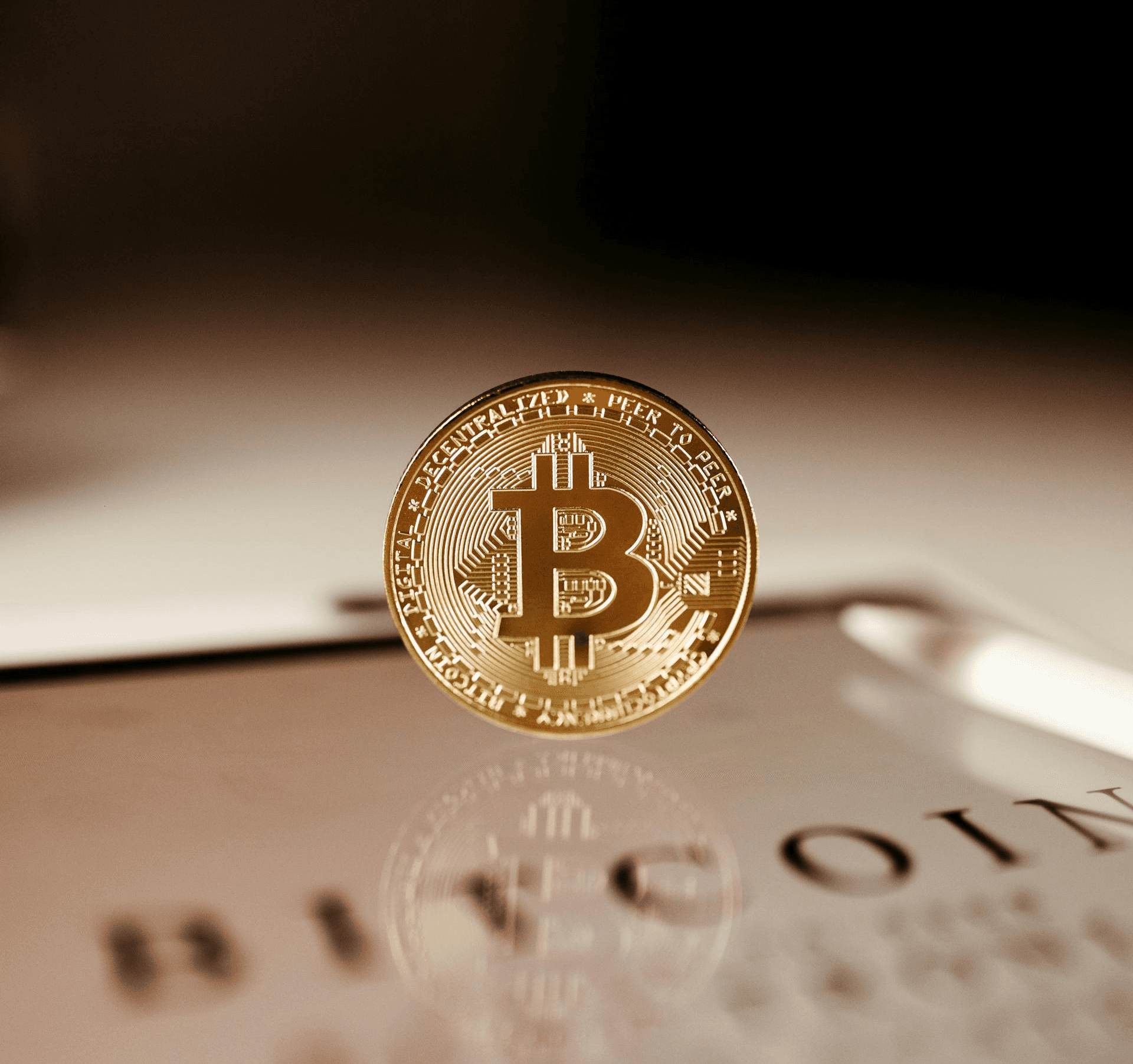 A bitcoin golden coin on its edge on top of a plain table