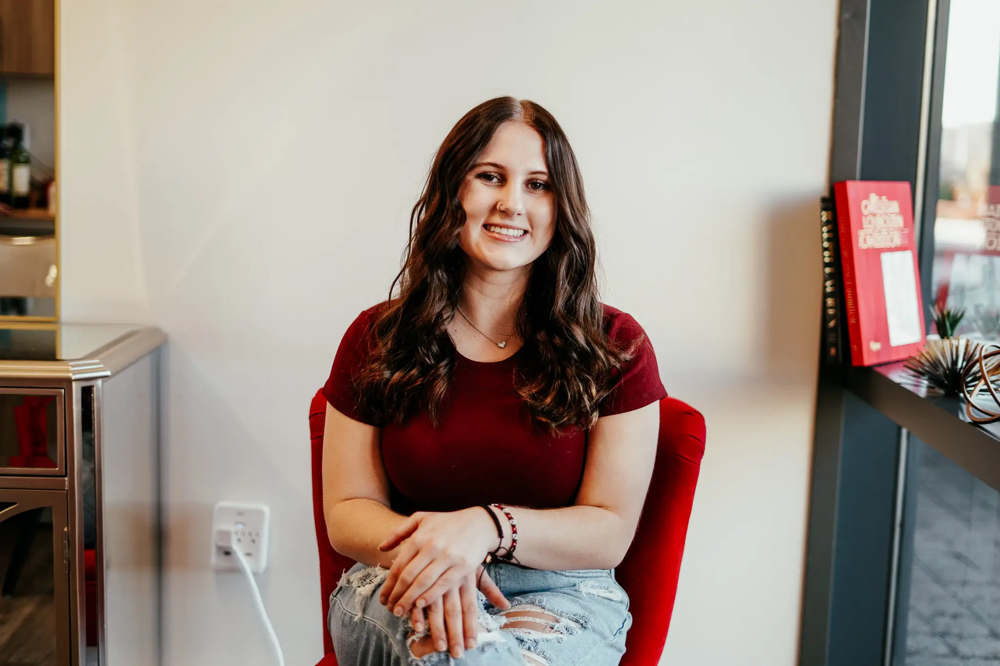 An image of Sloan Cain, a member of the admin team at Style Me Up Hair Extensions & Luxury Salon, sitting in a red chair.