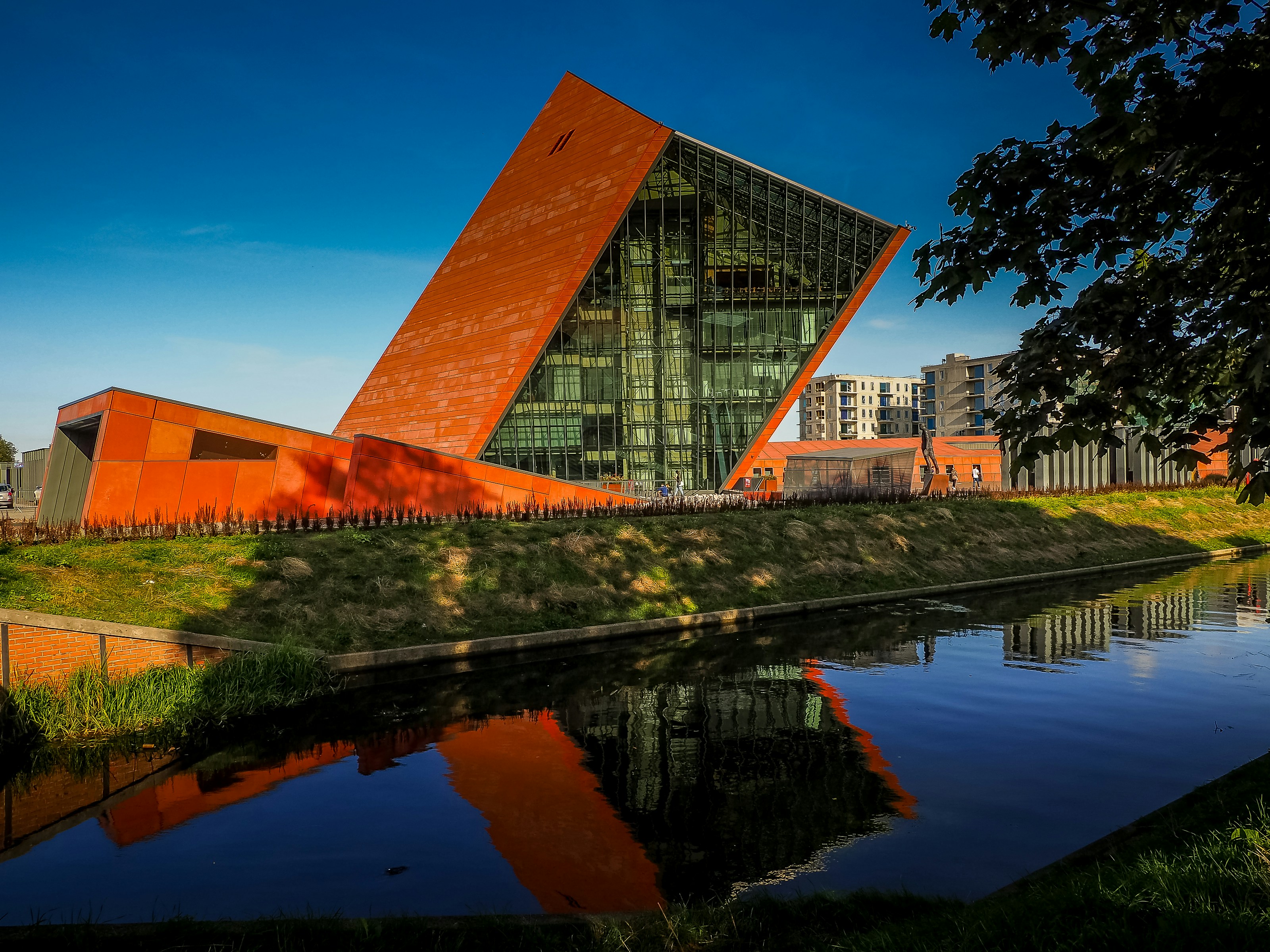 a building with a large orange triangle next to a body of water