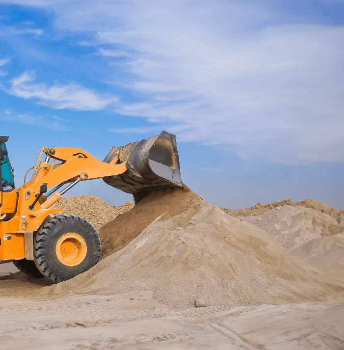 A loader dumping sand into a pile