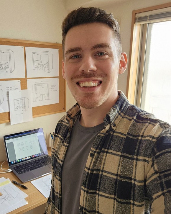 Portrait of a person in a pink sweater against a light background