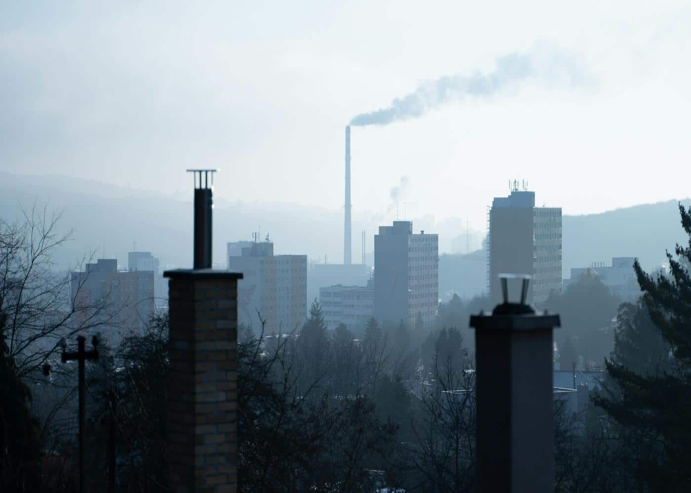 Pollution and mental health: grey city skyline polluted by a smokestack in the distance