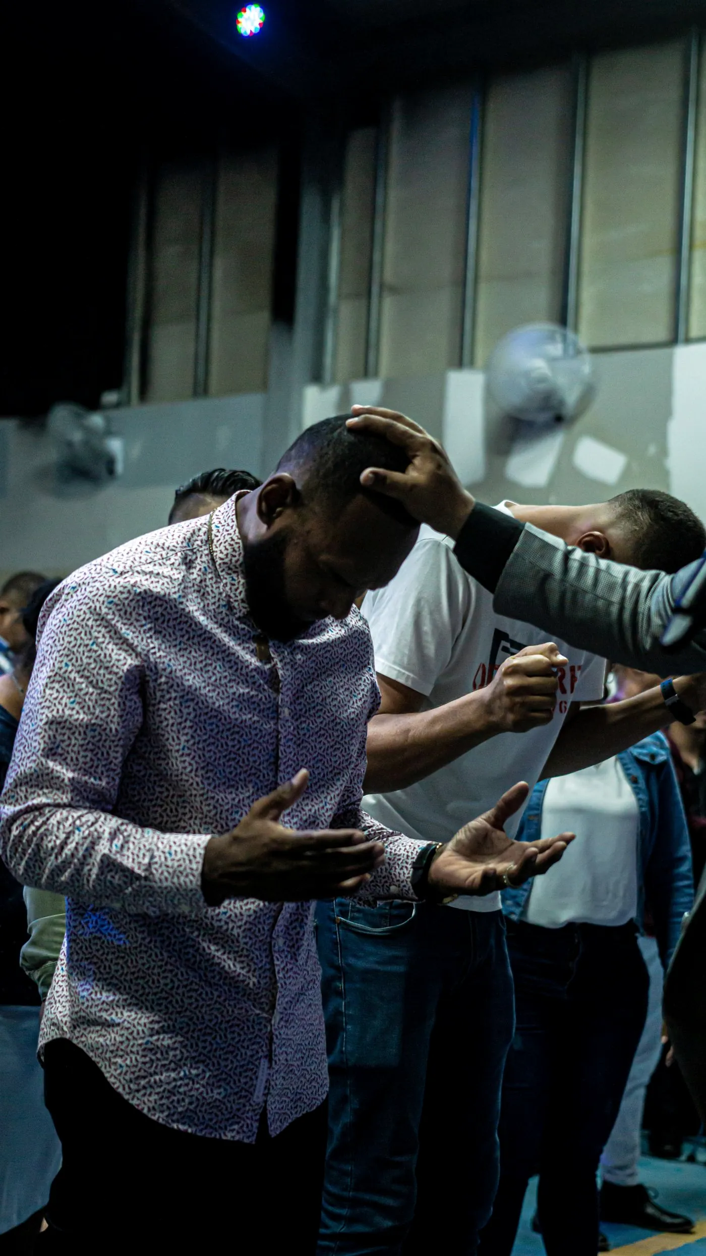 Friends praying over Kevin with their hands on his shoulders