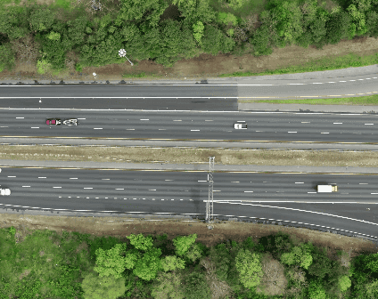 Aerial photo of a two-way highway, each lane with three traffic lanes, some cars and a truck.
