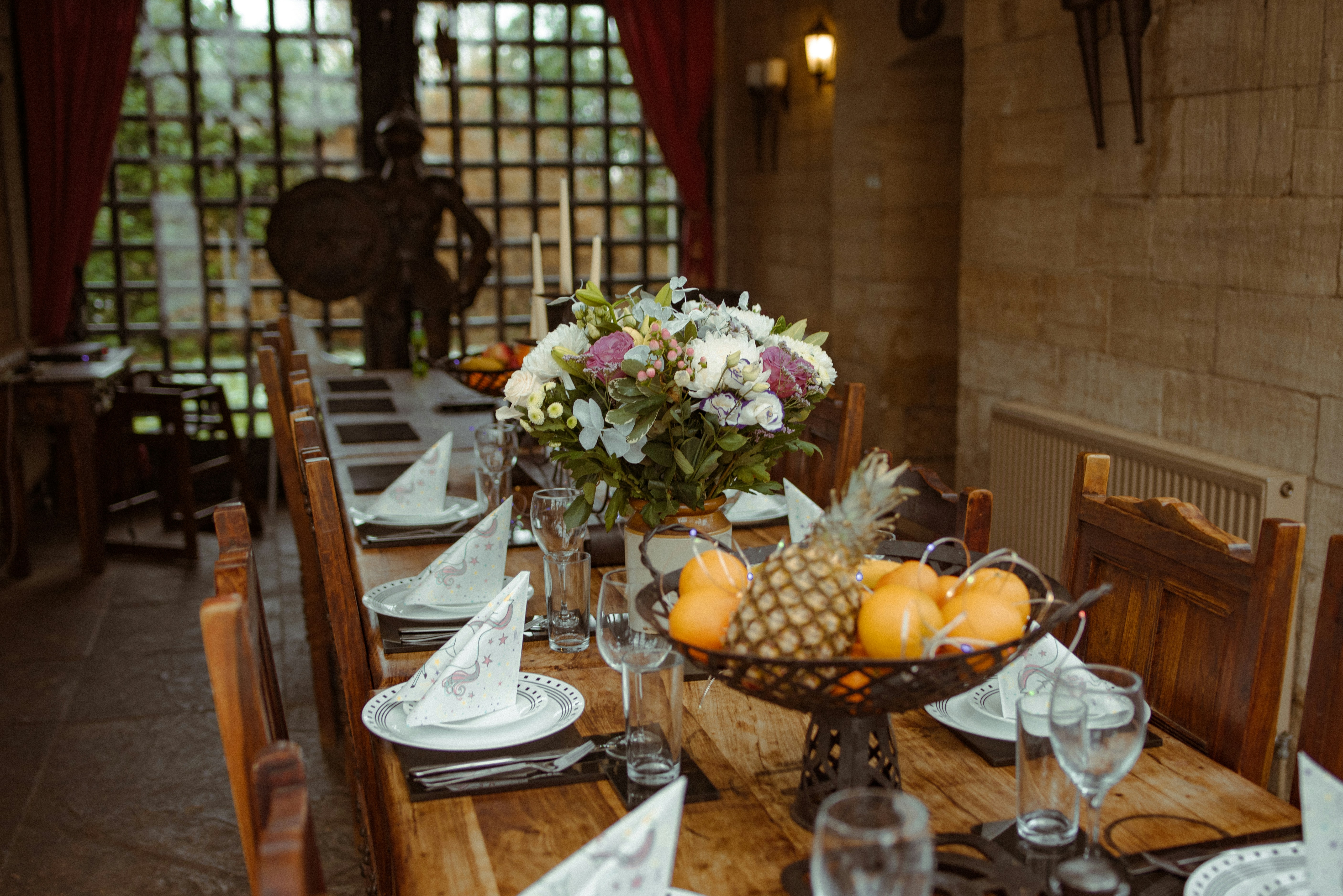A long dinner table set with flowers in a warm wood-paneled room