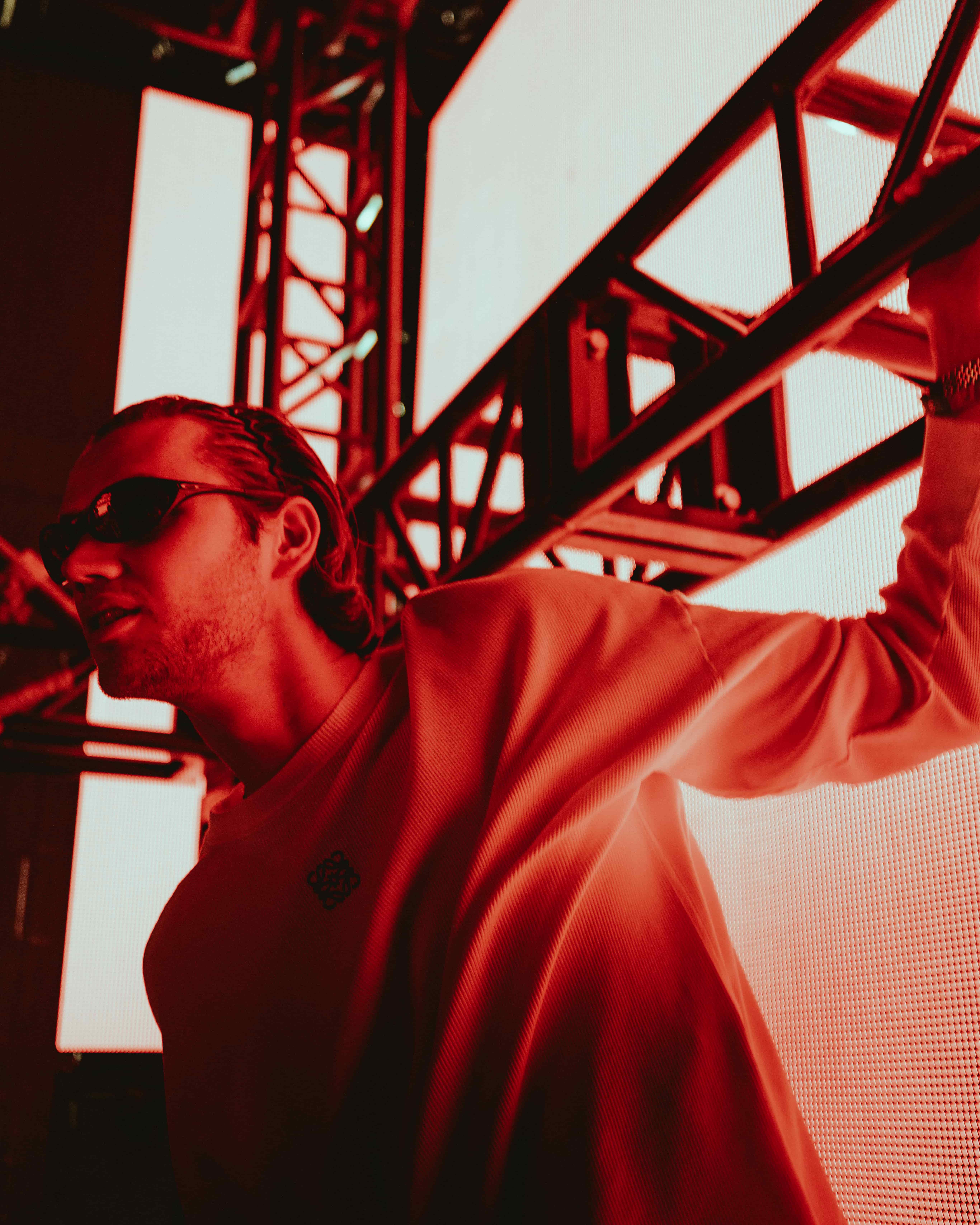 MAU P backstage at Coachella 2025 under red lighting near stage structure, captured by A World Away creative director Brandon Densley