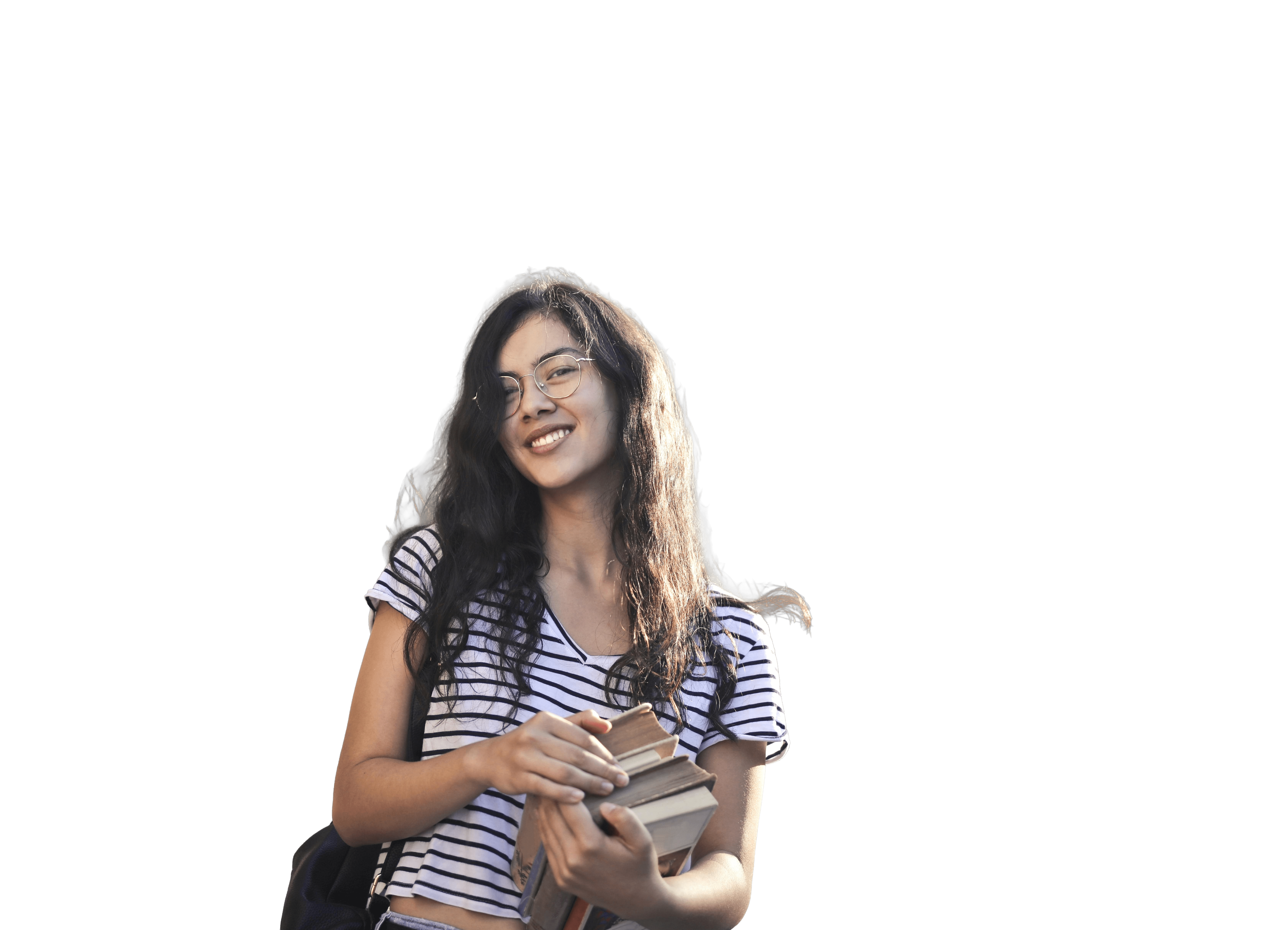 A smiling young woman with long wavy hair and glasses holds a stack of books while wearing a striped shirt and a backpack, standing against a plain background.