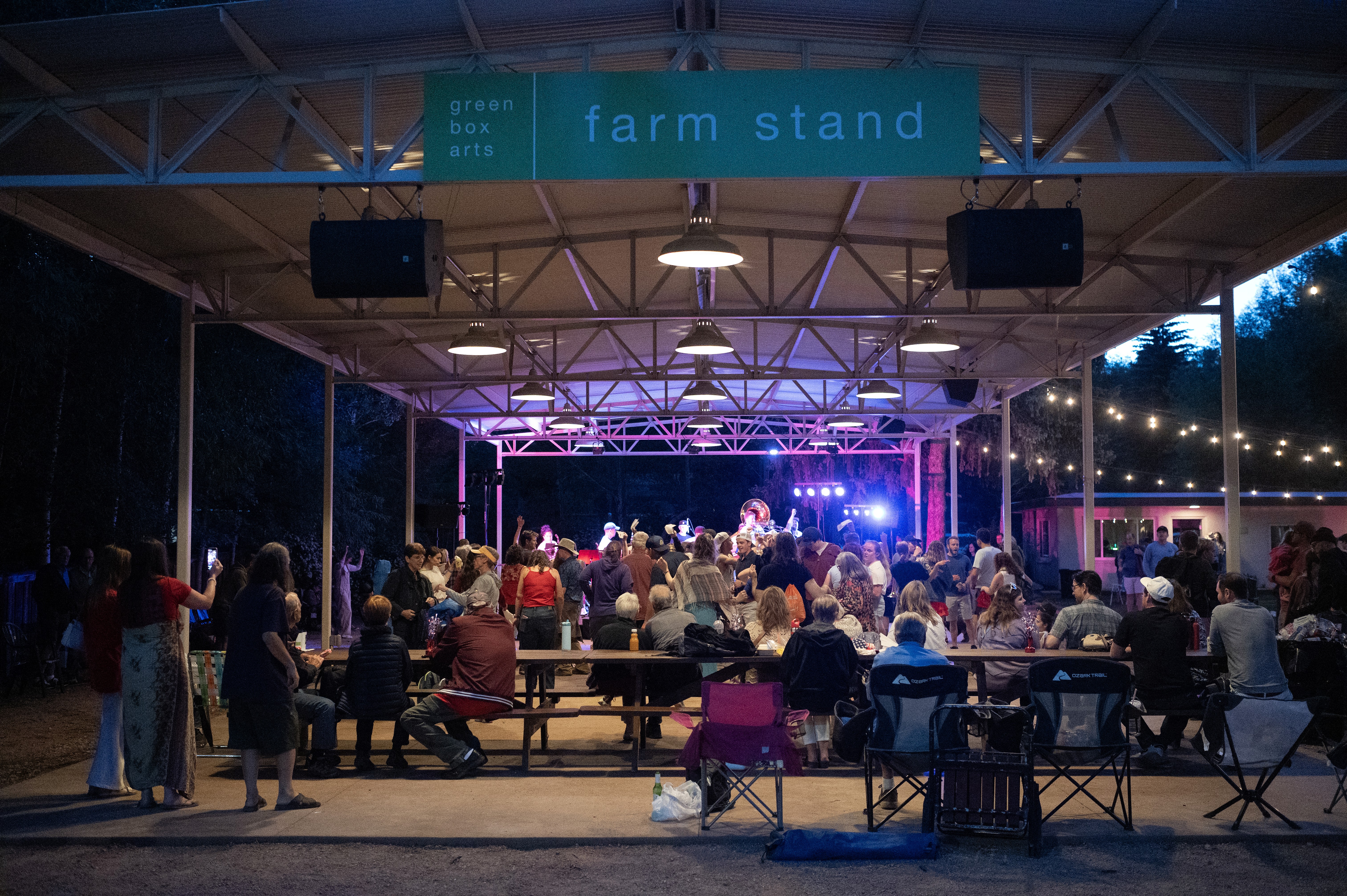People sitting outside by a stage