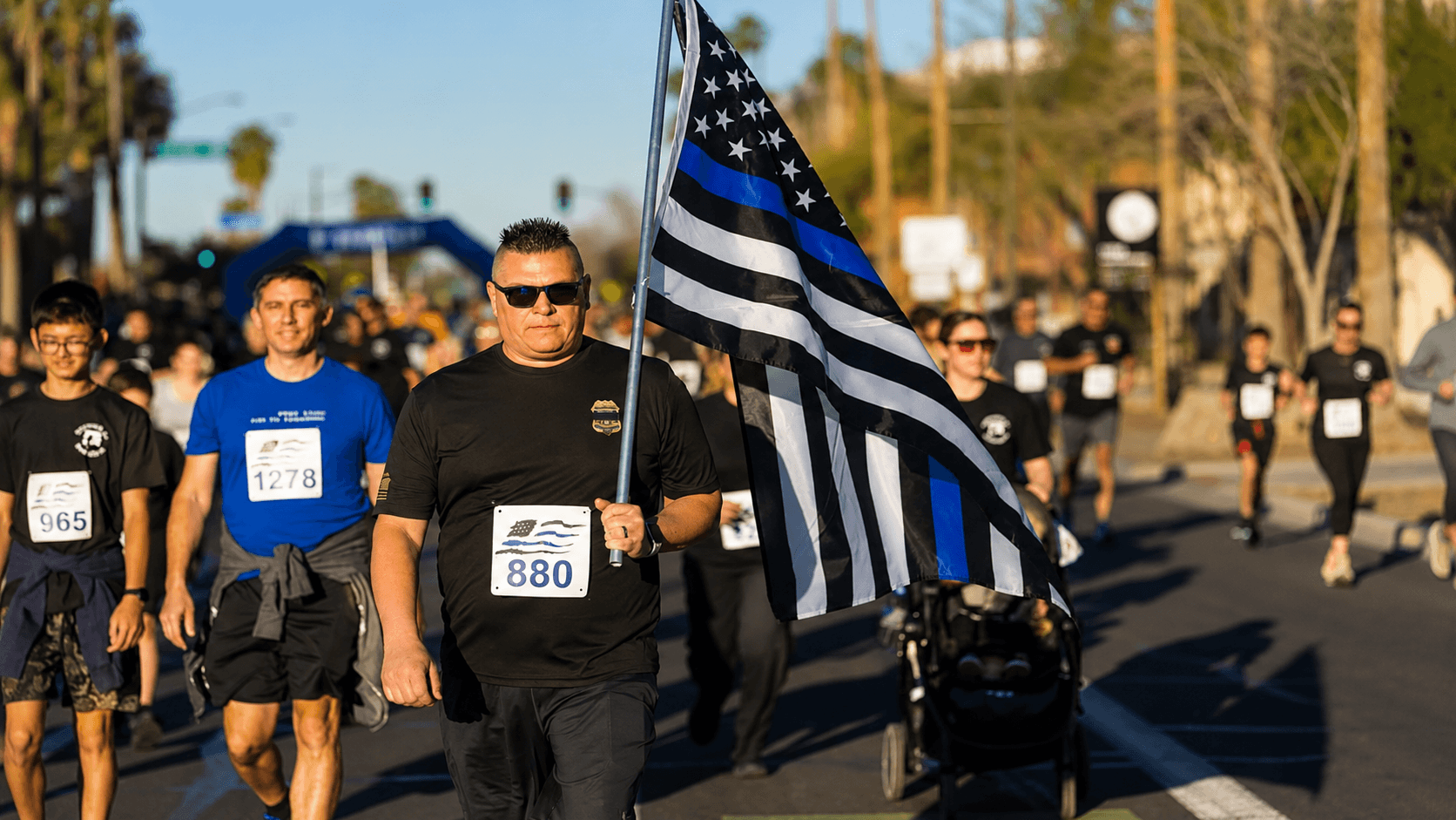 man walking with thin blue line flag at annual 5k