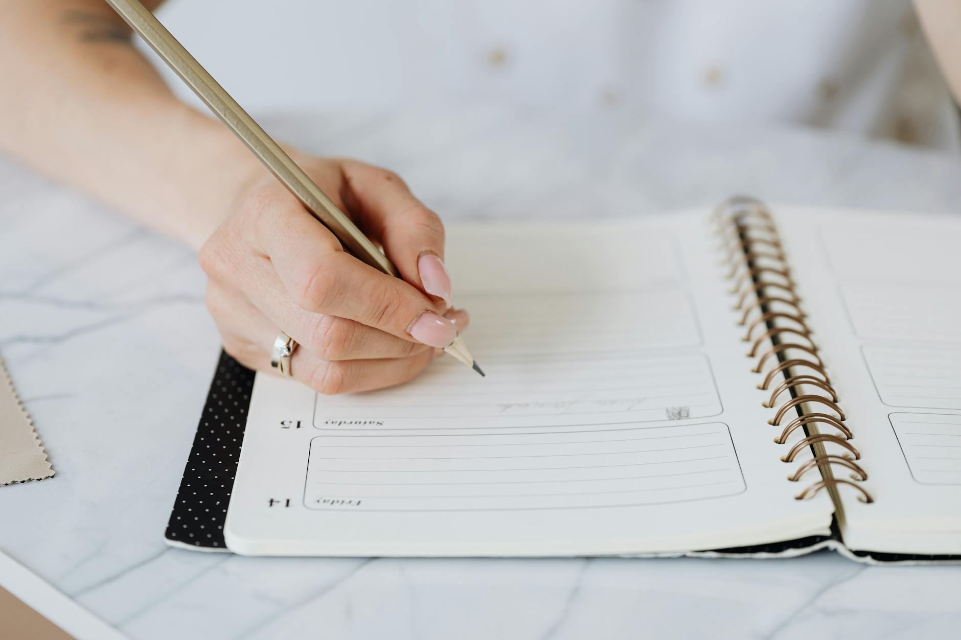 A teacher sitting at a low classroom table organizing printed schedule inserts into a bright blue three-ring binder.