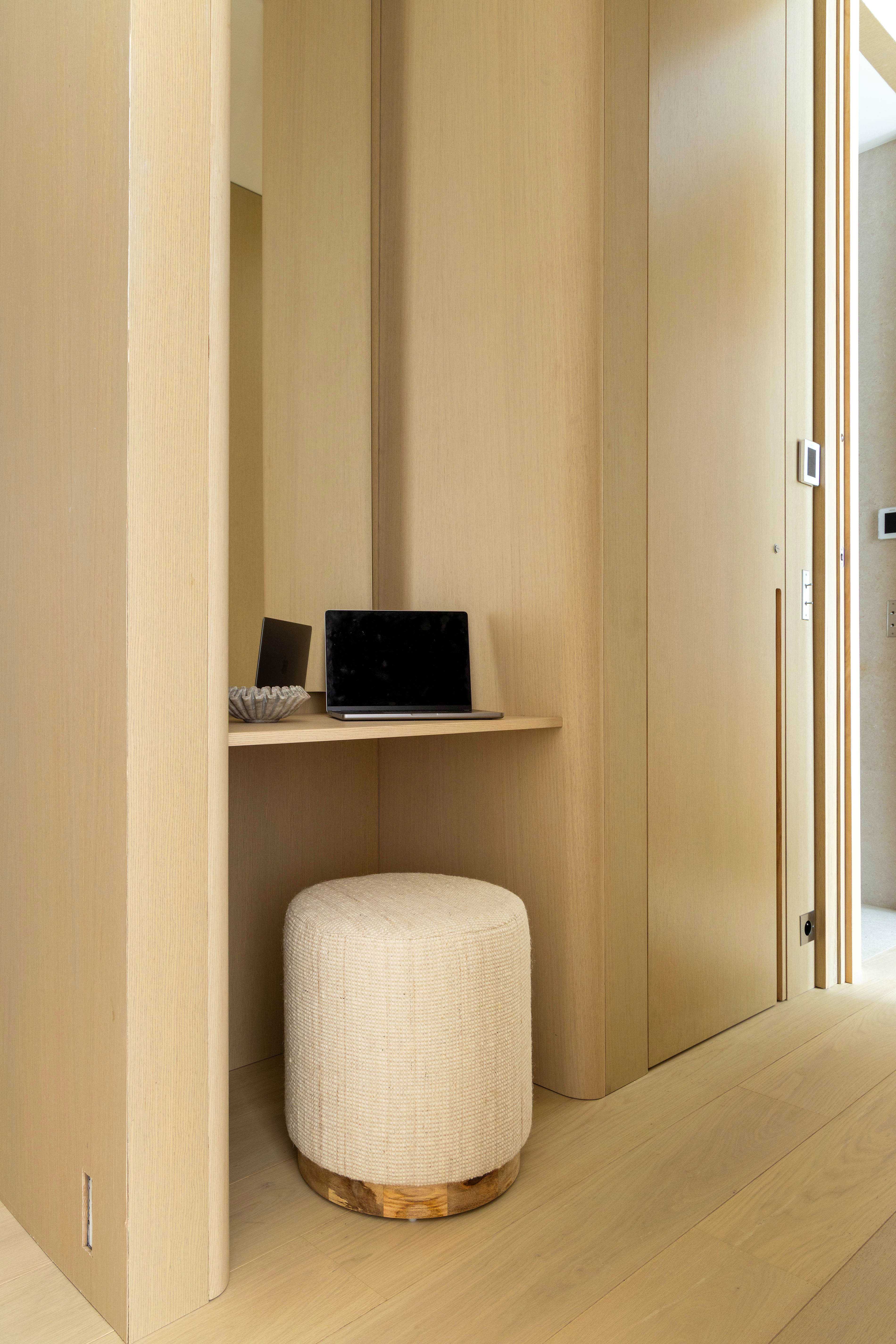 Bureau integre dans niche en bois clair avec tablette, ordinateur portable et pouf bouclette beige
