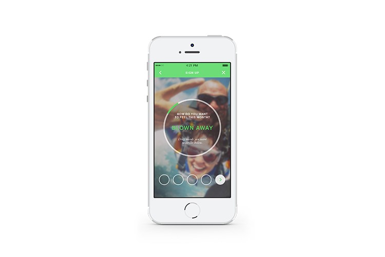 A white iPhone displays a mobile app interface. The screen shows a circular graphic with the text "HOW DO YOU WANT TO FEEL THIS MONTH?" in green. Below it, a blurred image of a man and woman is visible. Four white circles are arranged horizontally at the bottom of the screen. A green bar at the top shows the time as 4:21 PM and indicates "Sign Up." A small "X" icon appears in the top right corner.