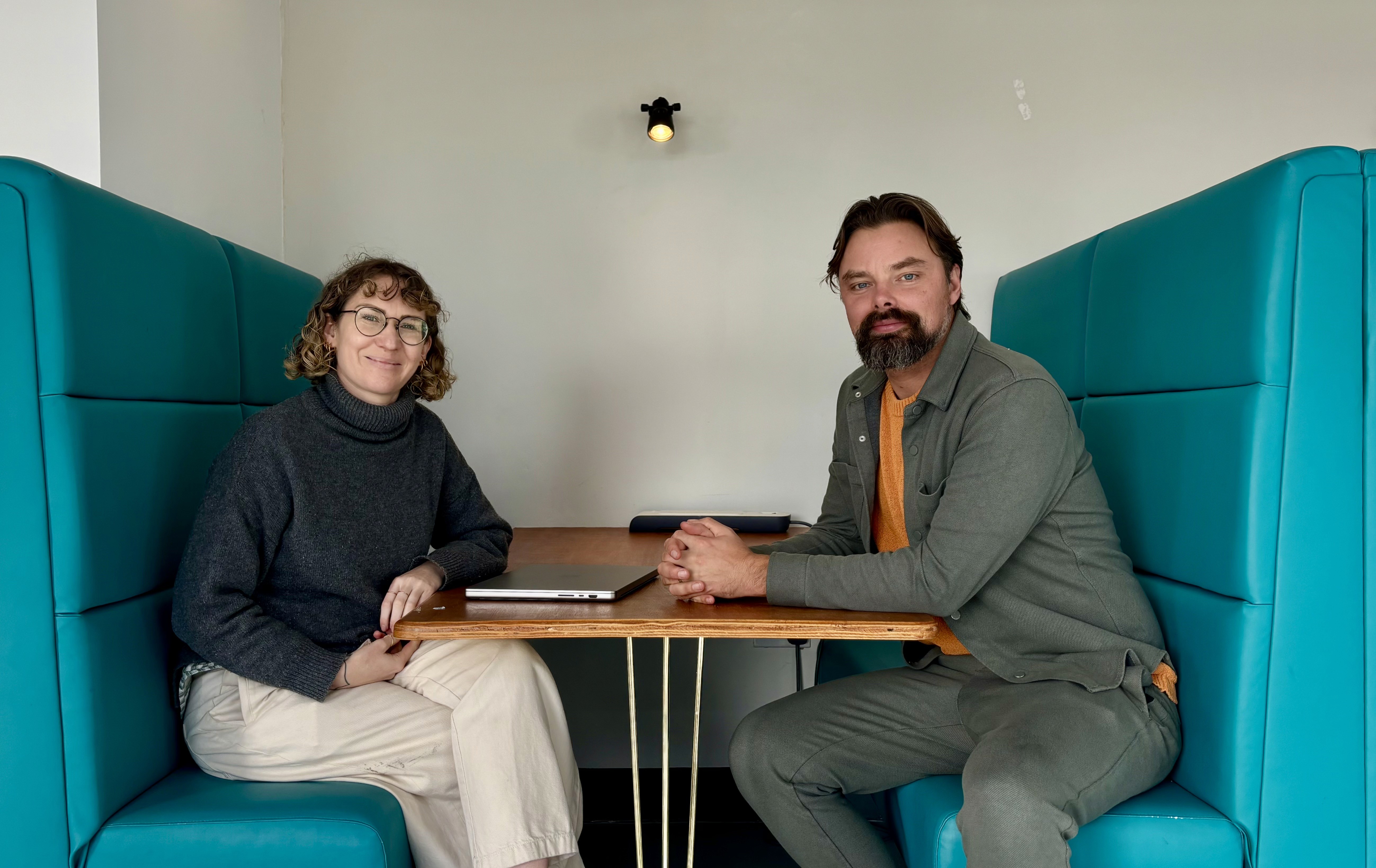 Two people sitting on a green couch using an open laptop.