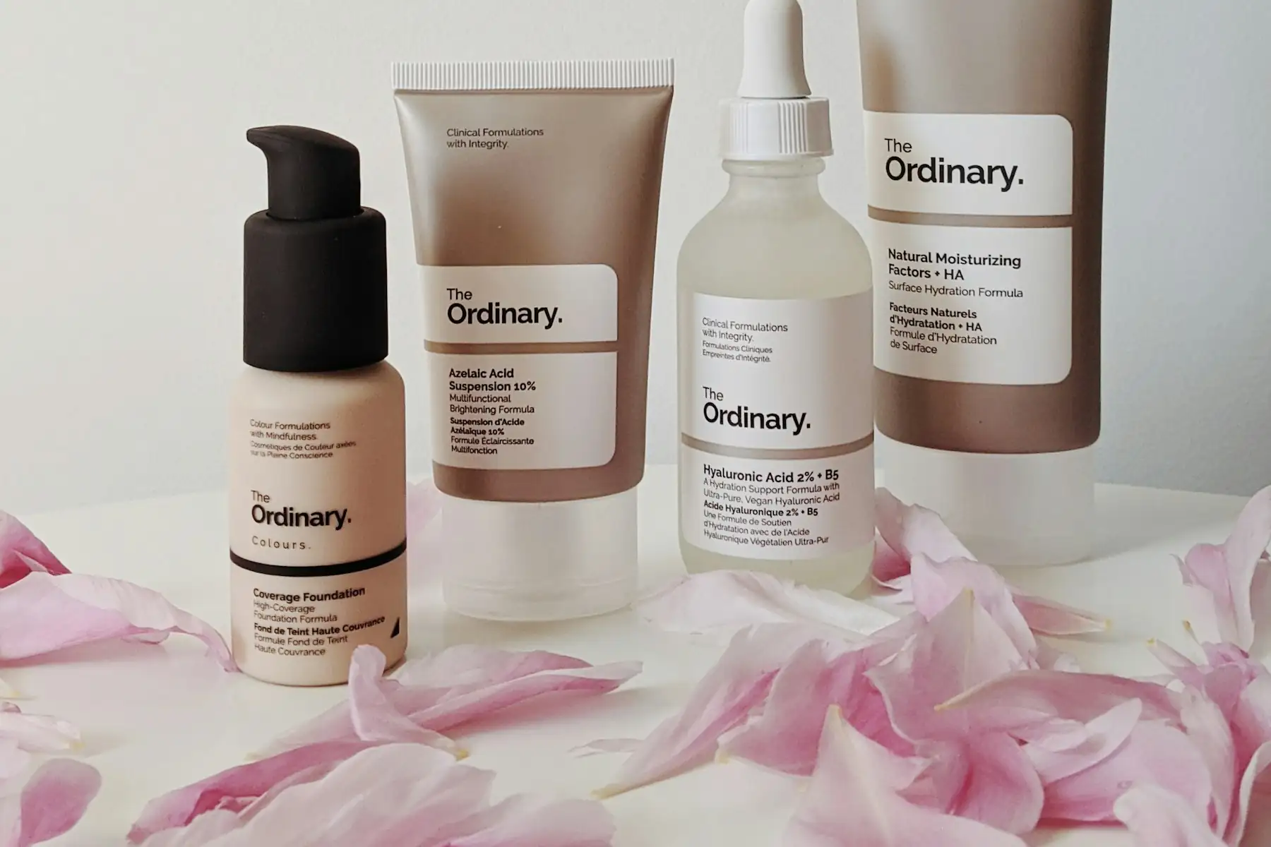 A lineup of minimalist skincare bottles and droppers on a pale beige surface