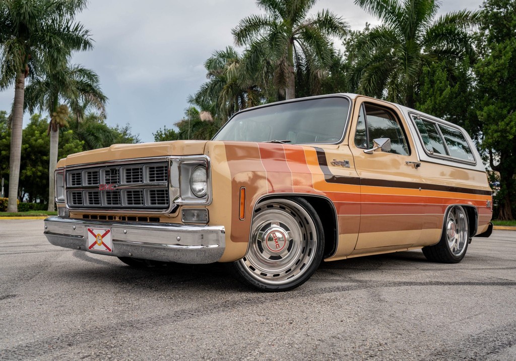 Vintage GMC SUV with a custom brown, orange, and beige paint job, freshly detailed with a shiny finish, parked near palm trees on a clear day in Southwest Florida.