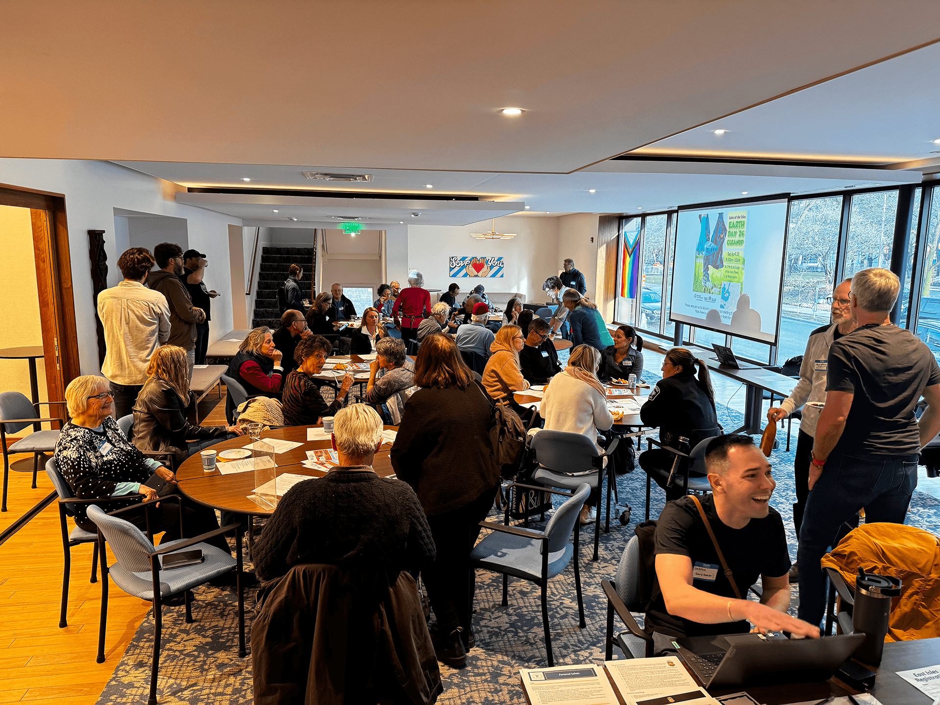 Grace Trinity Church members seated at tables and engaged in discussion during a church meeting in a bright room with floor-to-ceiling windows.