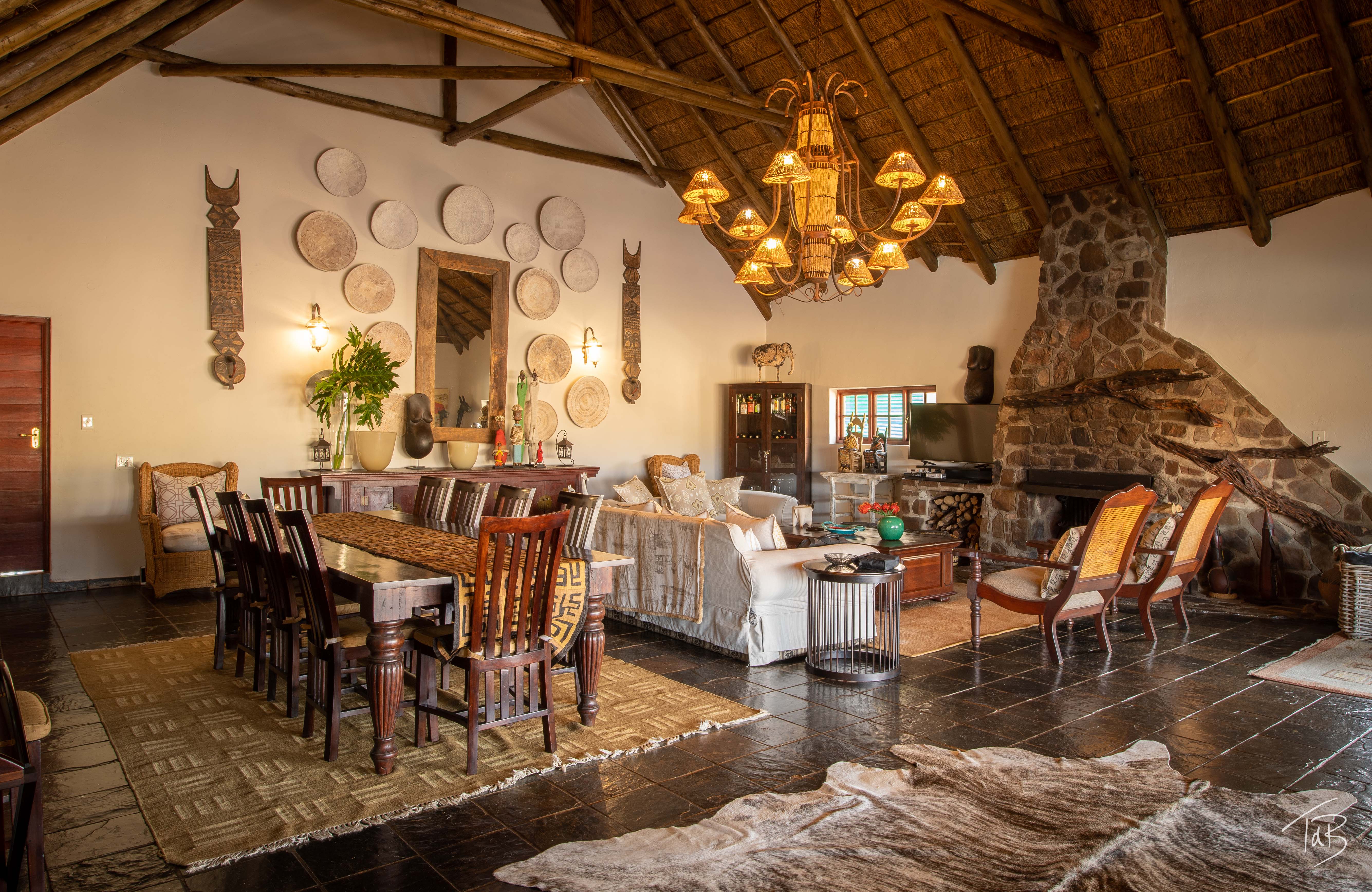 African Explorer, Waterberg, Sydafrika. Savannah Lodge main area. Vackert och rustikt inredd lounge area med middagsbord, soffor, eldstad och vacker belysning. På ridsemester i Afrika