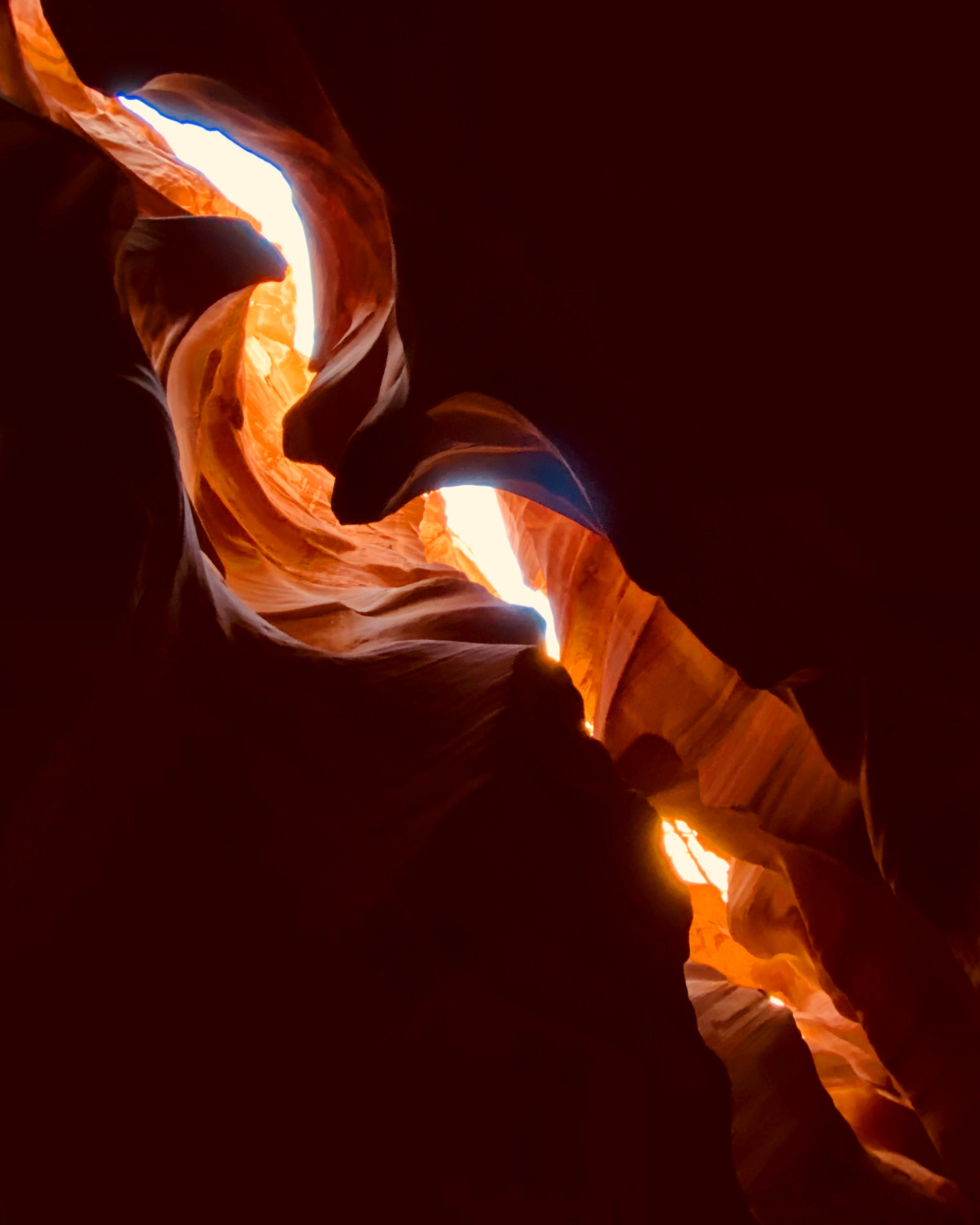 A swirling plume of orange and yellow flame against a dark background, creating an abstract, dynamic effect.