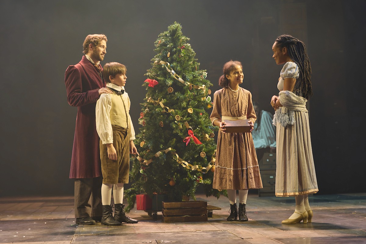 A Christmas Carol scene with a family gathered around a Christmas tree.