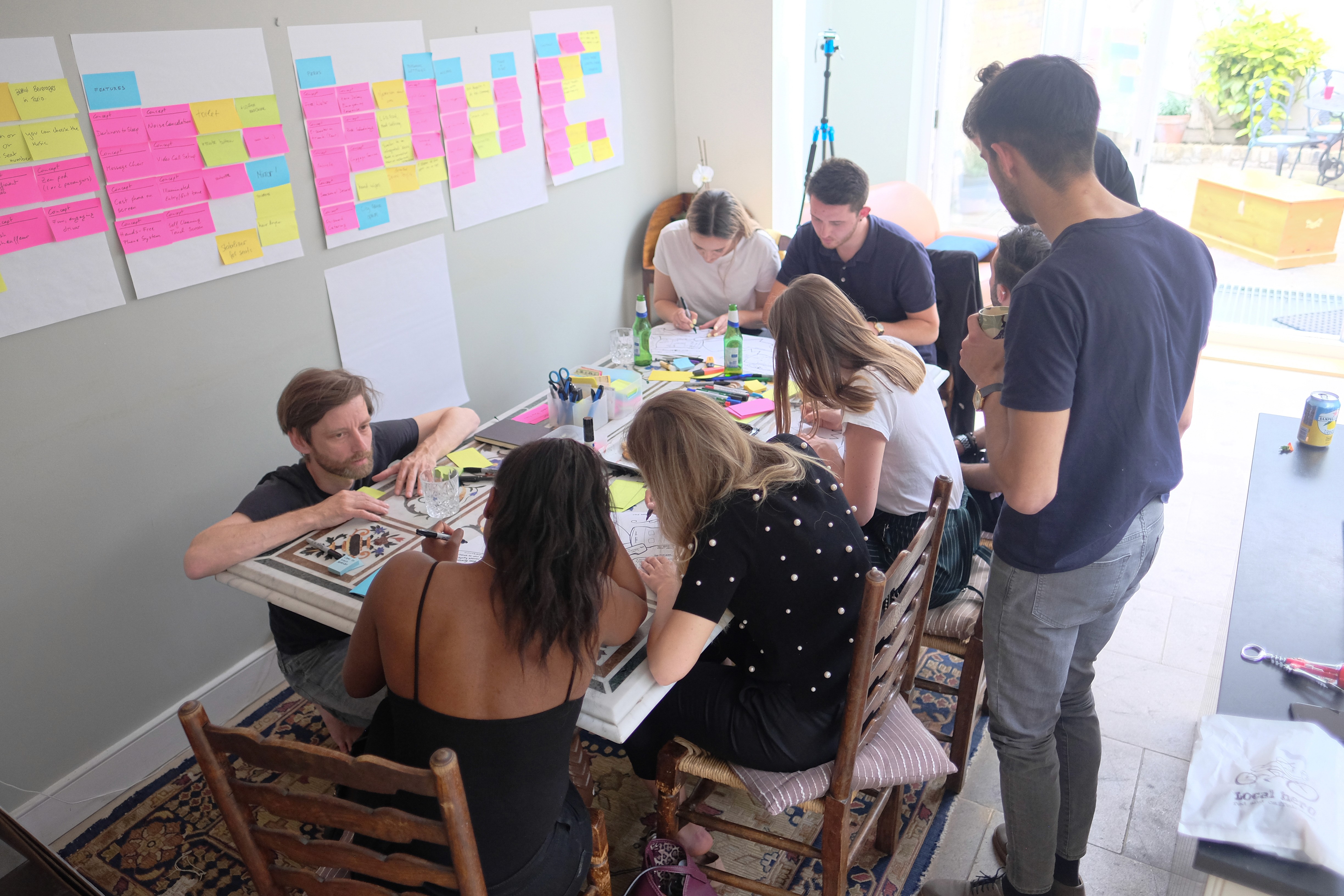 Group research session. Sketching at the table, sticky notes on the walls.
