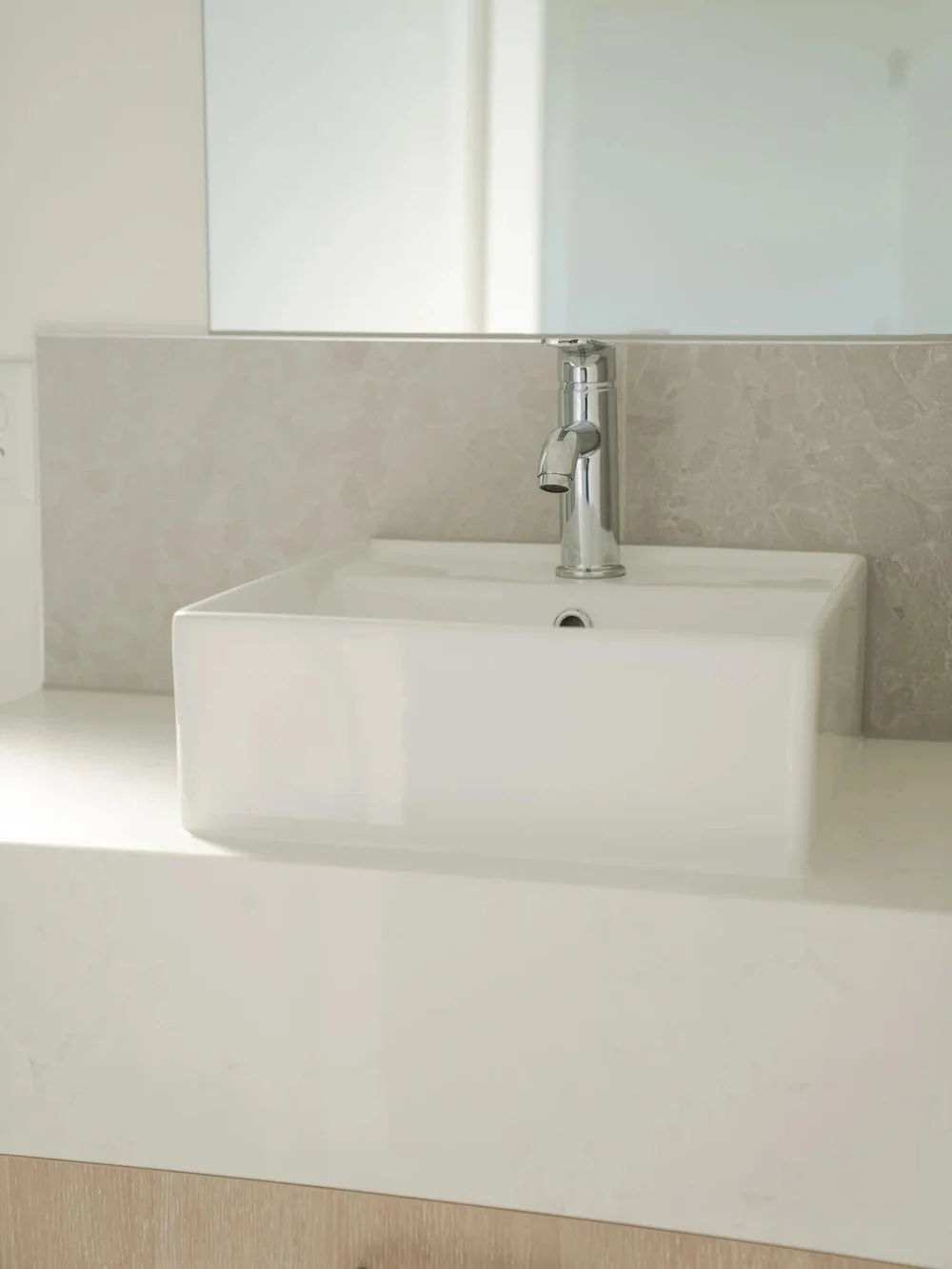 Modern bathroom sink with chrome faucet and marble backsplash.