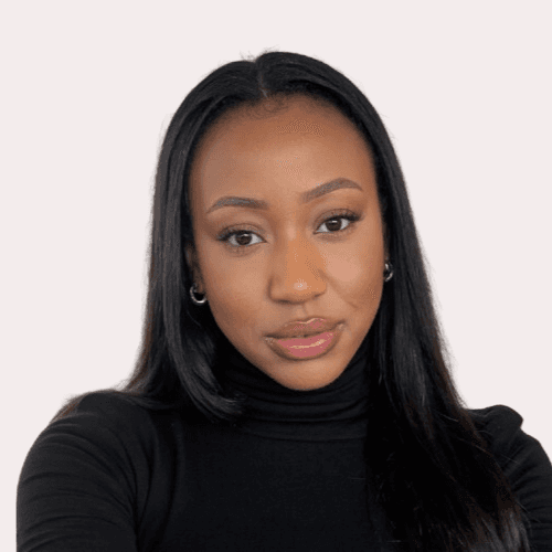 A person stands outdoors in a natural setting with lush green trees under a clear sky, wearing a dark sweatshirt, and looking into the distance.