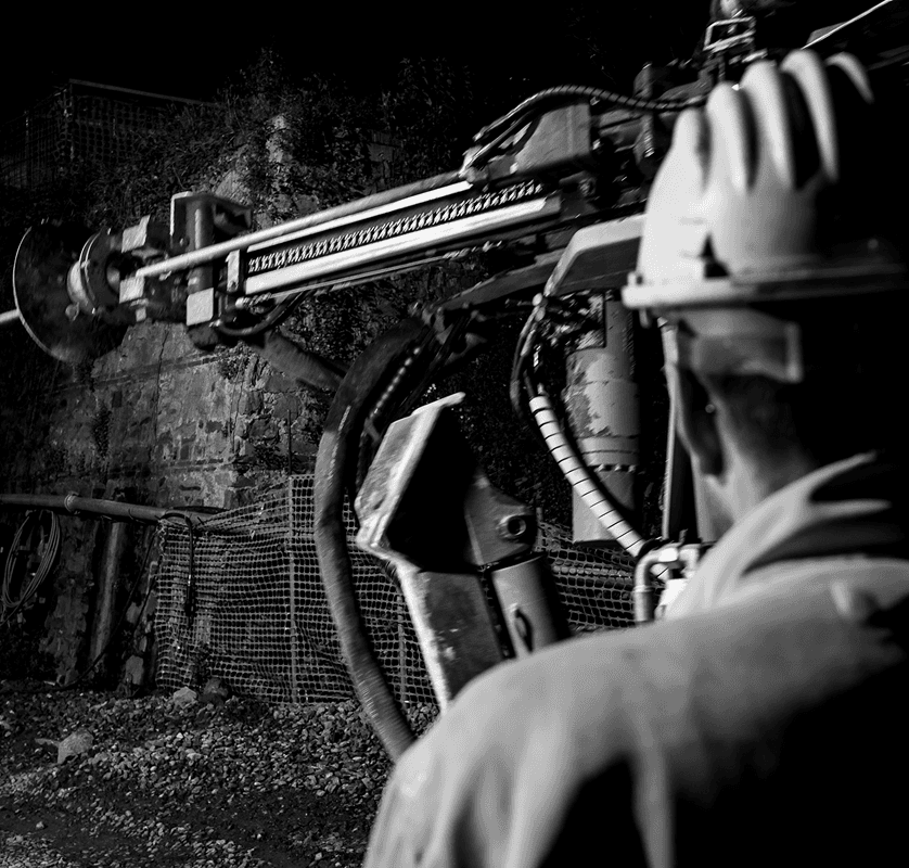 Operatore specializzato al lavoro con trivella per perforazioni in cantiere, immagine in bianco e nero