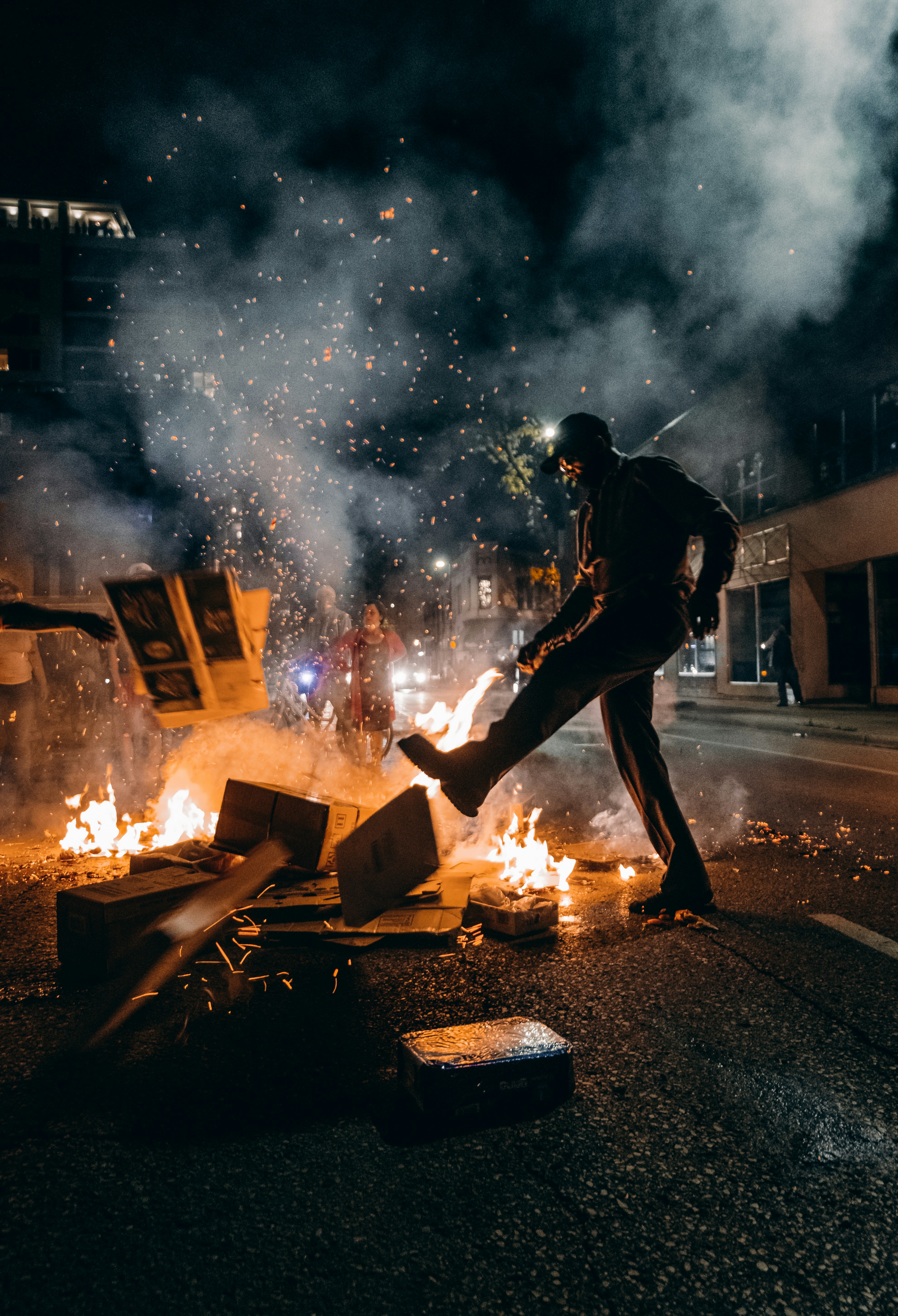 Man kicking object on a fire at night