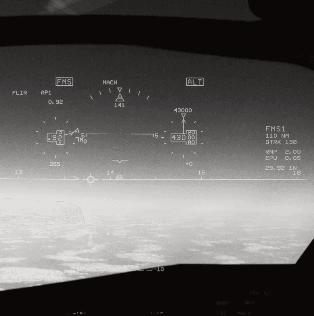 A black and white image depicting a blurred landscape with faint, ambiguous shapes in the foreground and background.