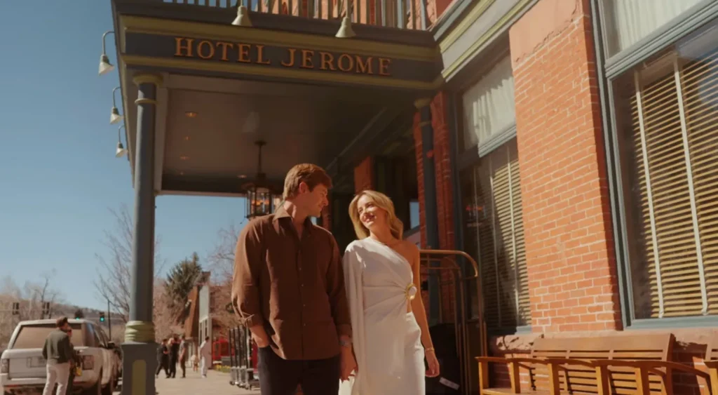 Newly engaged couple walking out of Hotel Jerome entrance on Main Street in Aspen Colorado