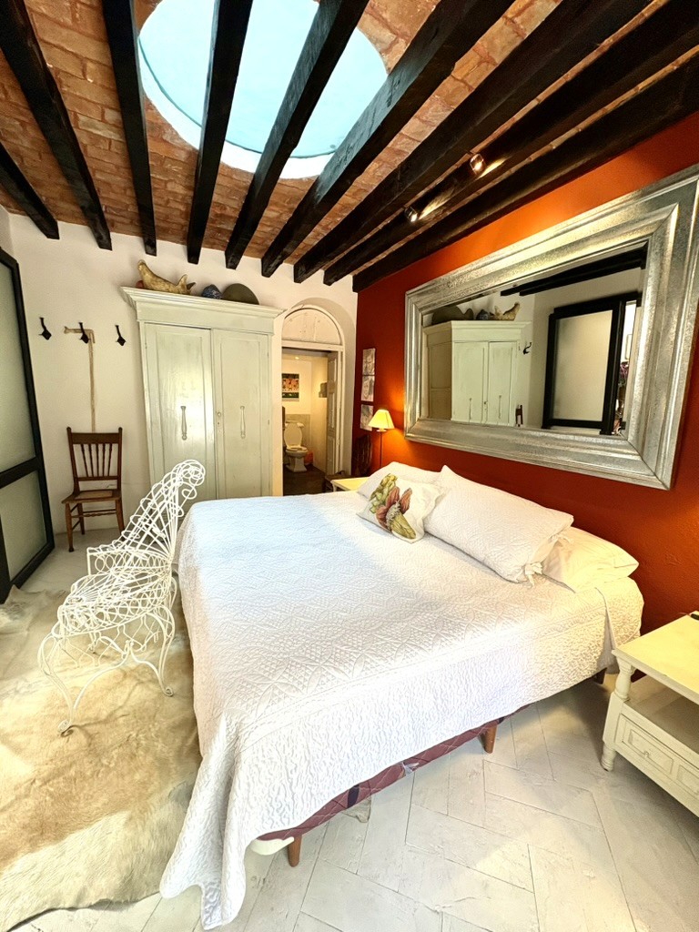 Red-wall bedroom with circular skylight at Casa de los Tíos
