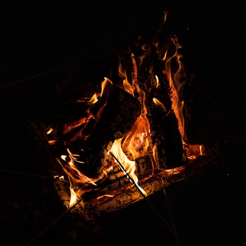 在昏暗环境中，明亮的火焰正燃烧着木柴。
